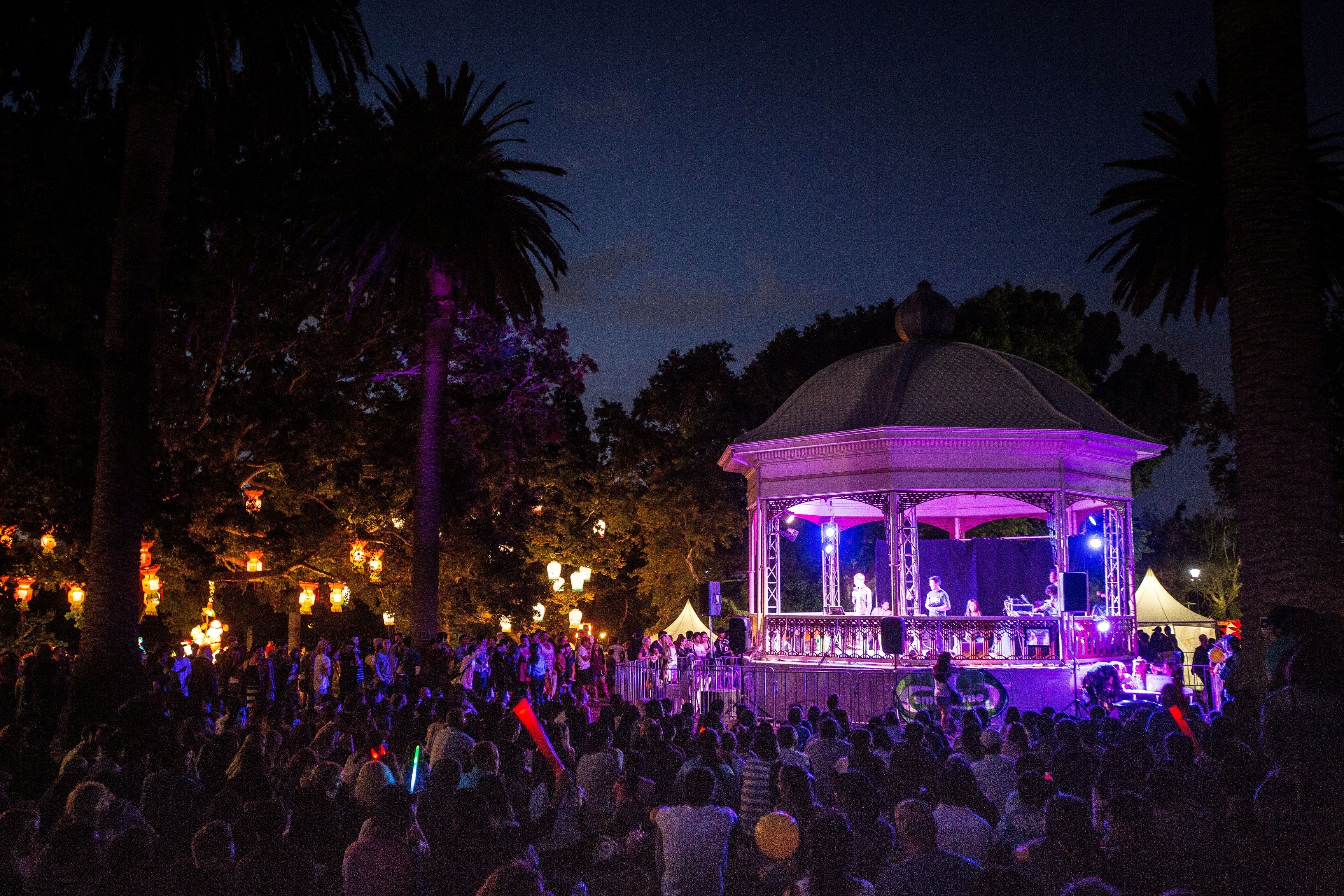 A crowd in a park standing around a rotunda
