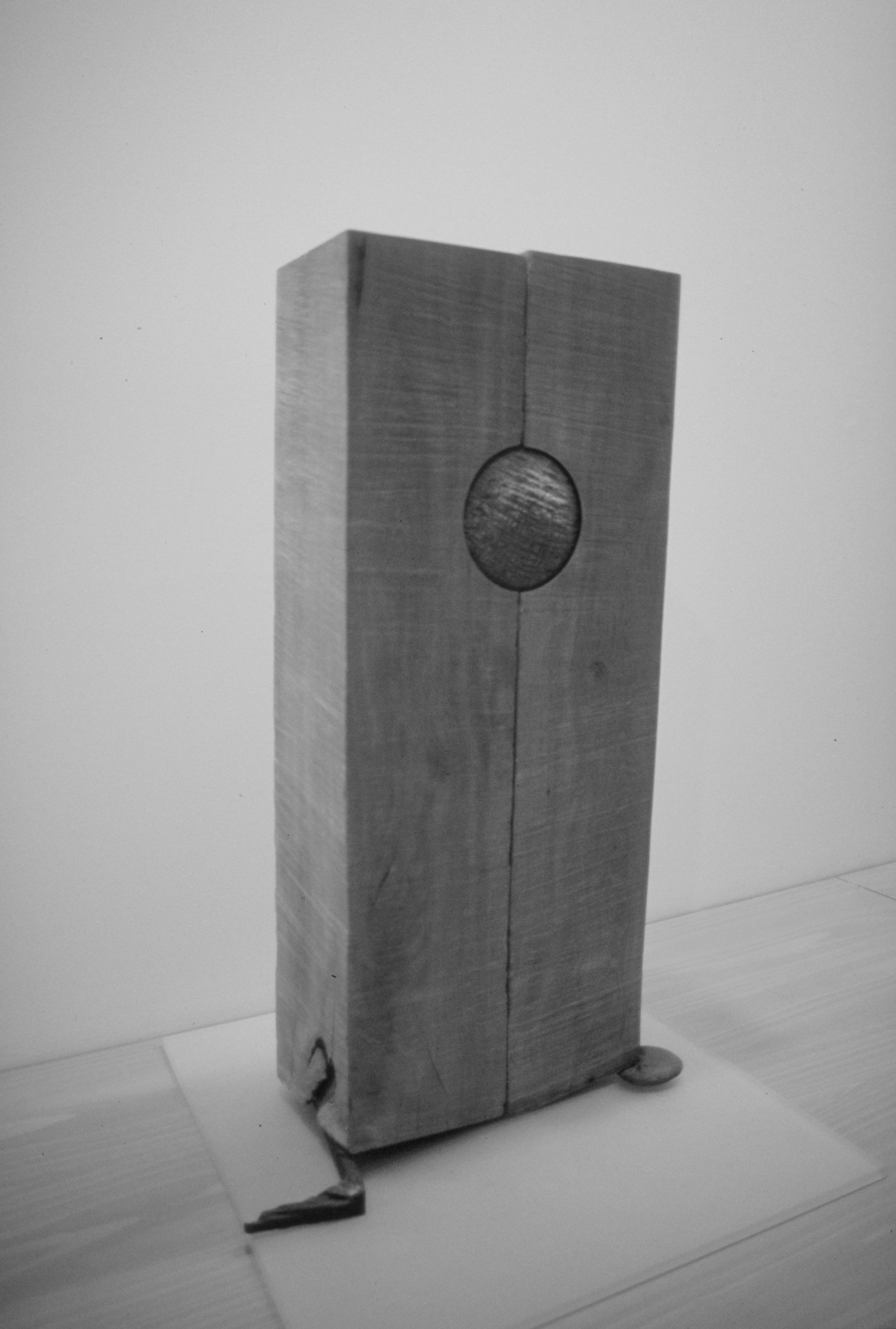 a rectangular wood sculpture with a sphere in the middle