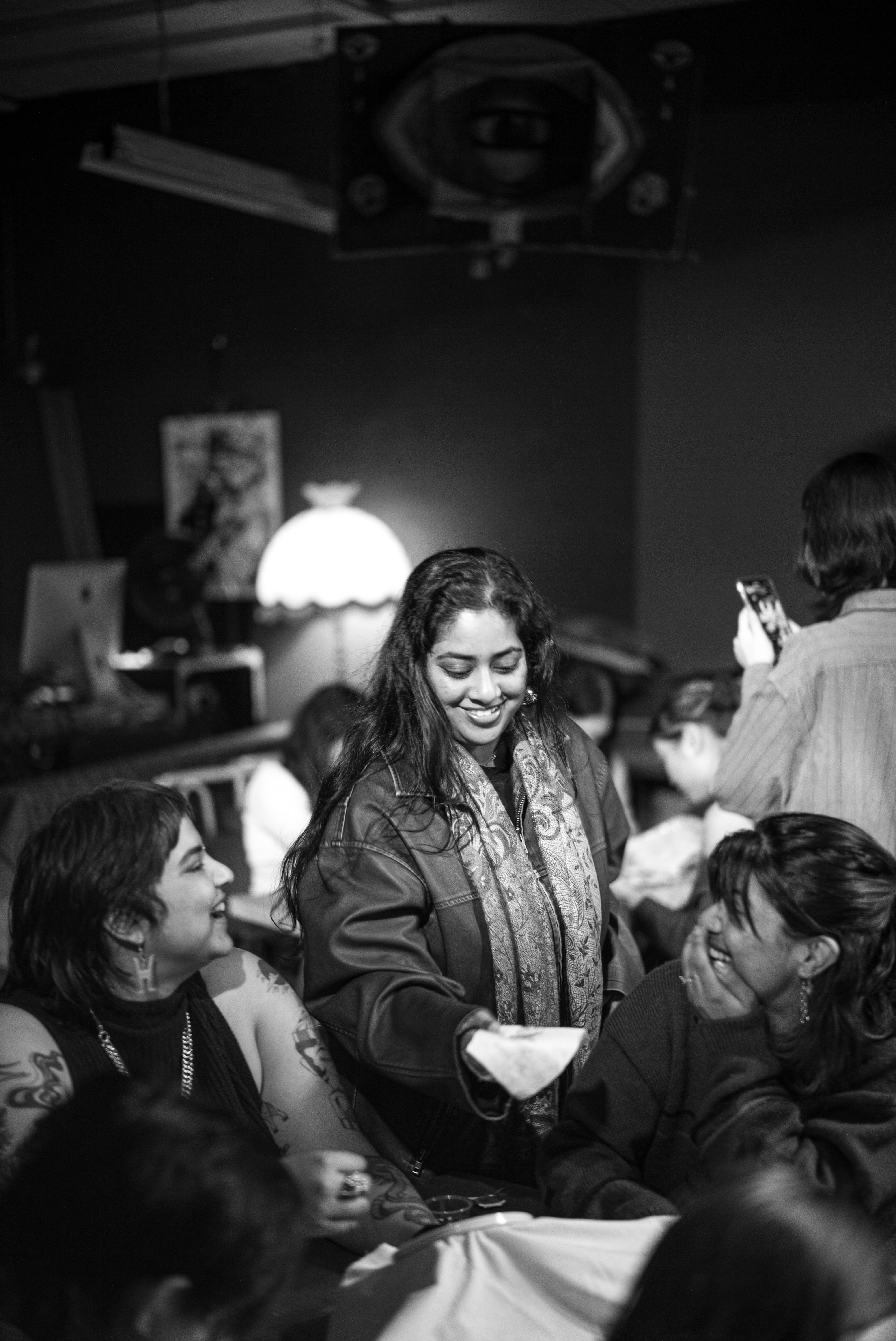 Black and white photo of a person standing in a room with other people