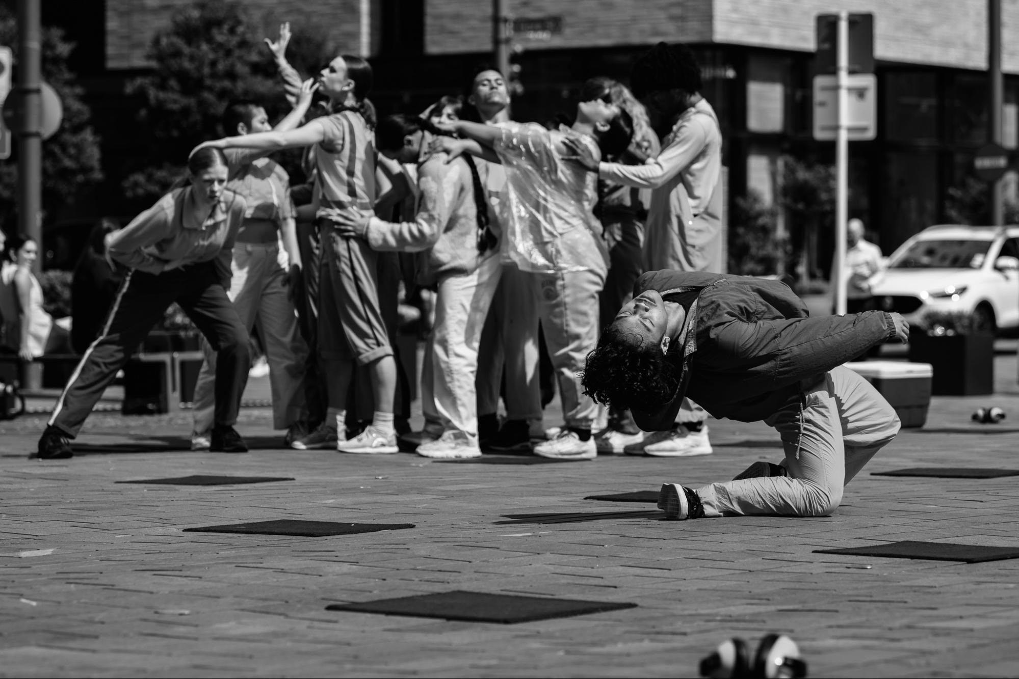 Black and white action photo of a Filipino-person in the foreground doing a vogue dip while other performers in the background are looking on