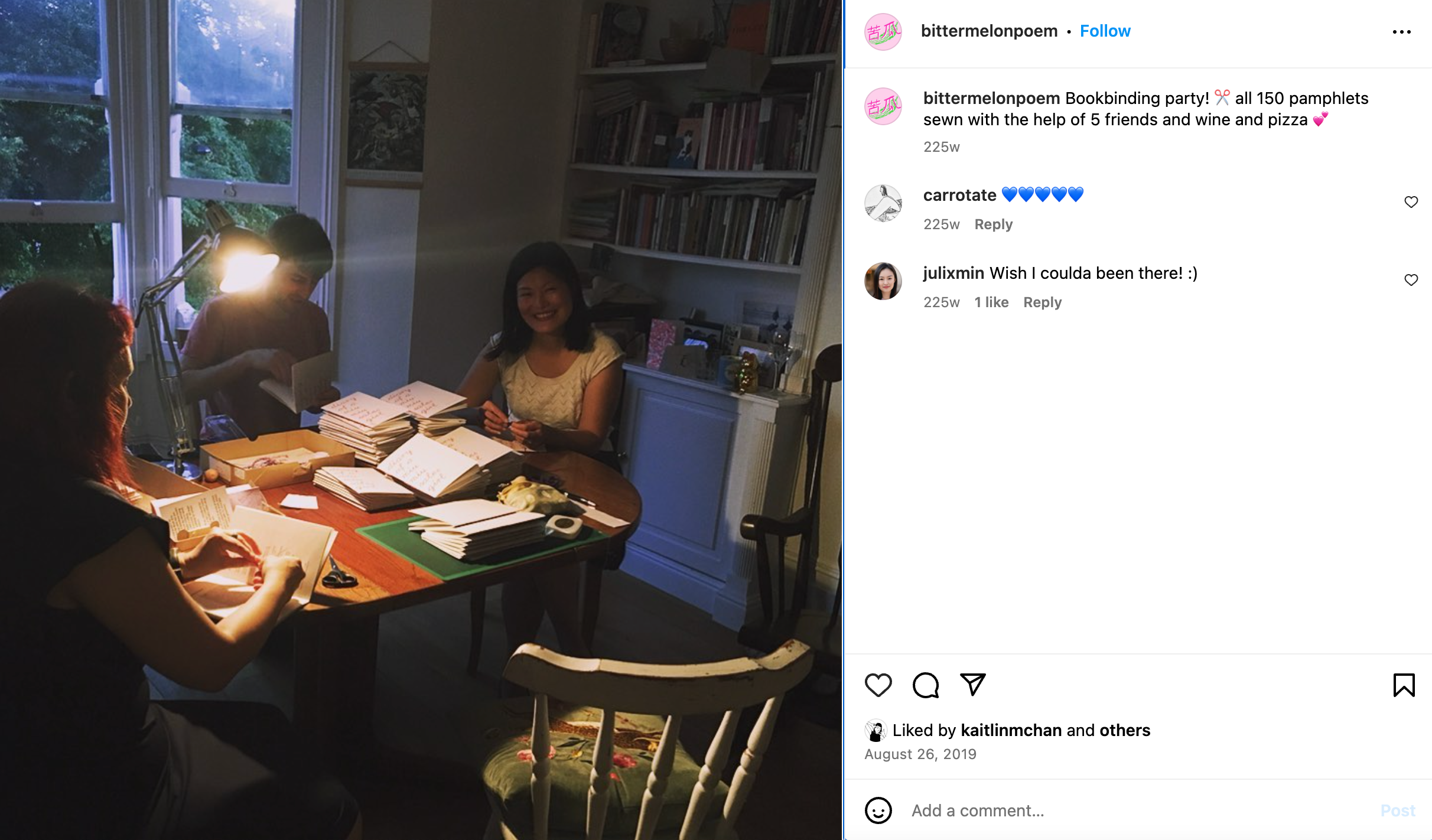 A photo of three people smiling and binding zines with a stack of pages on the table in front of them.