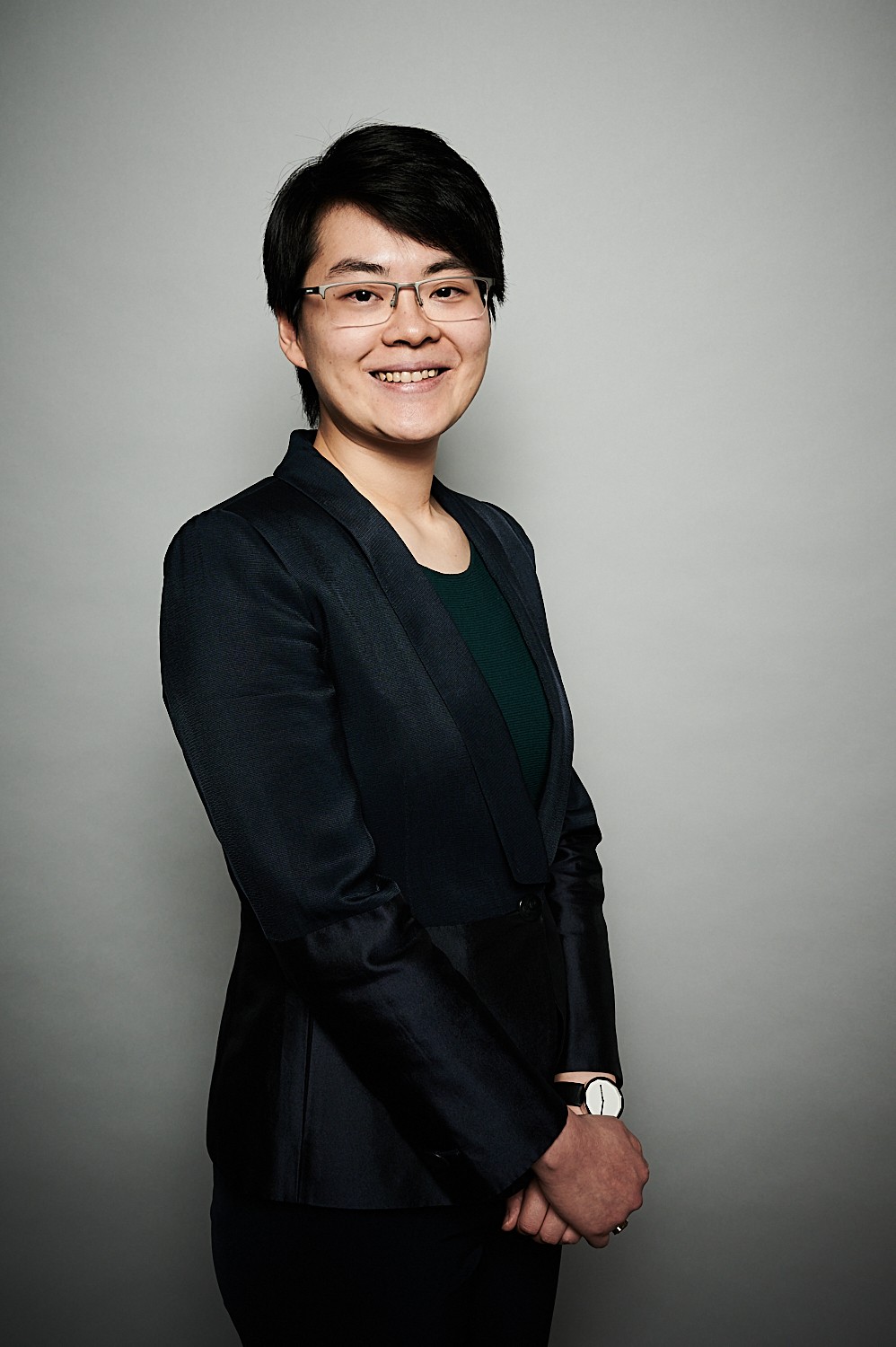 A pereson in a black suit and glasses smiling 