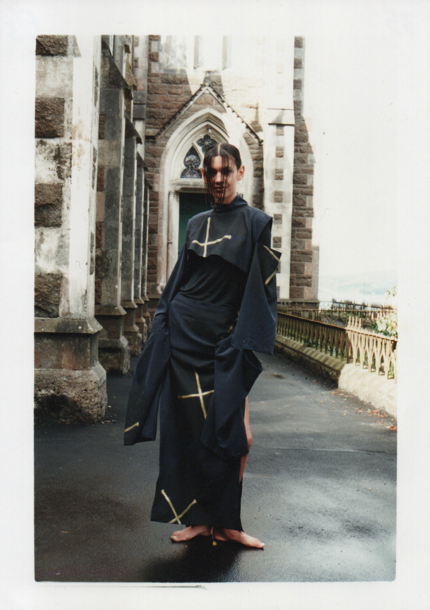 A woman wearing a draped black dress with stars standing outside a church