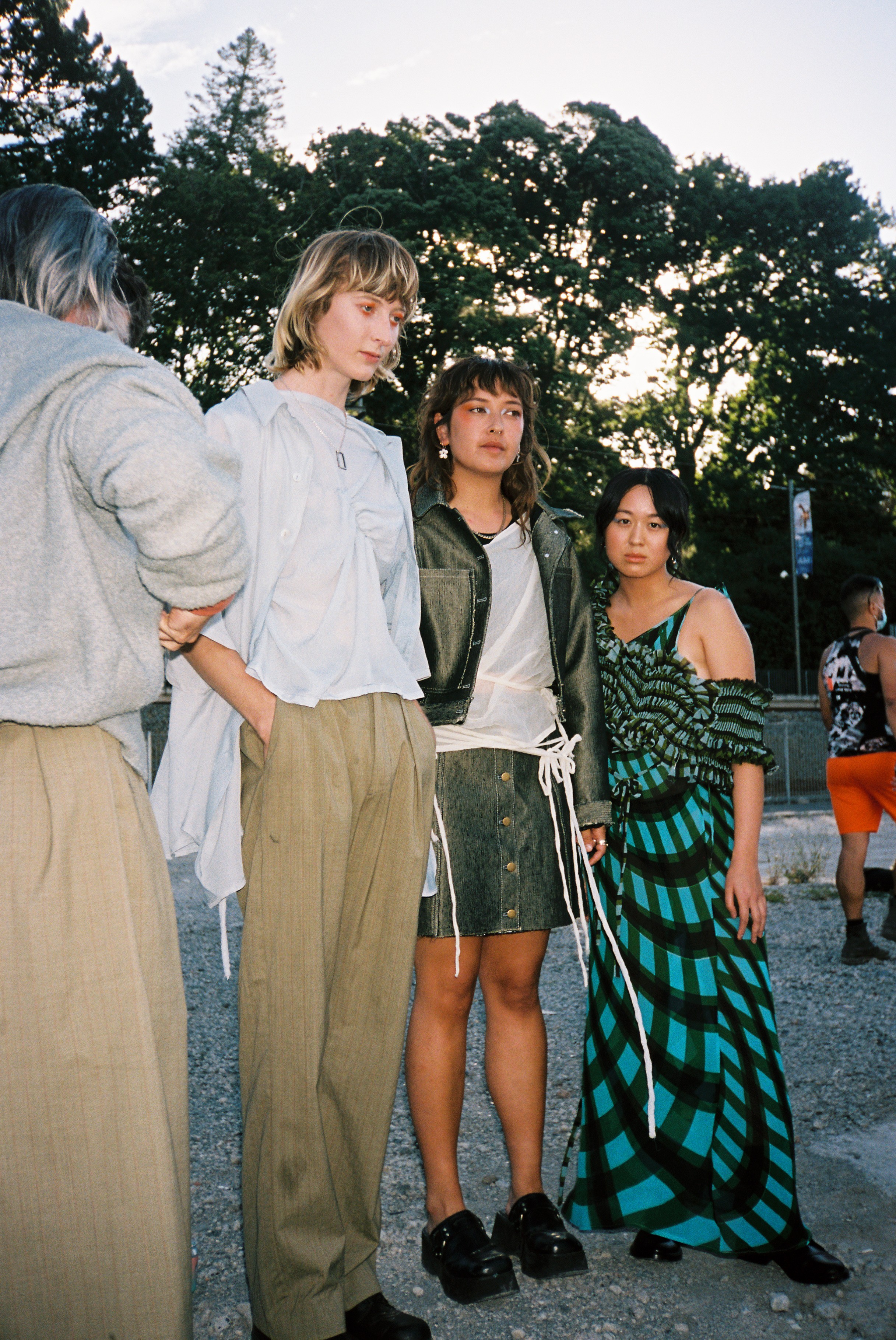 Three models stand casually at a fashion show