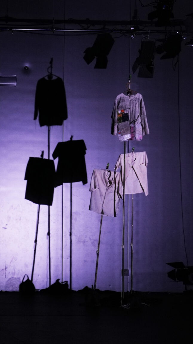 Three shirts made out of recycled Asian rice bags hangs on three tall bamboo poles