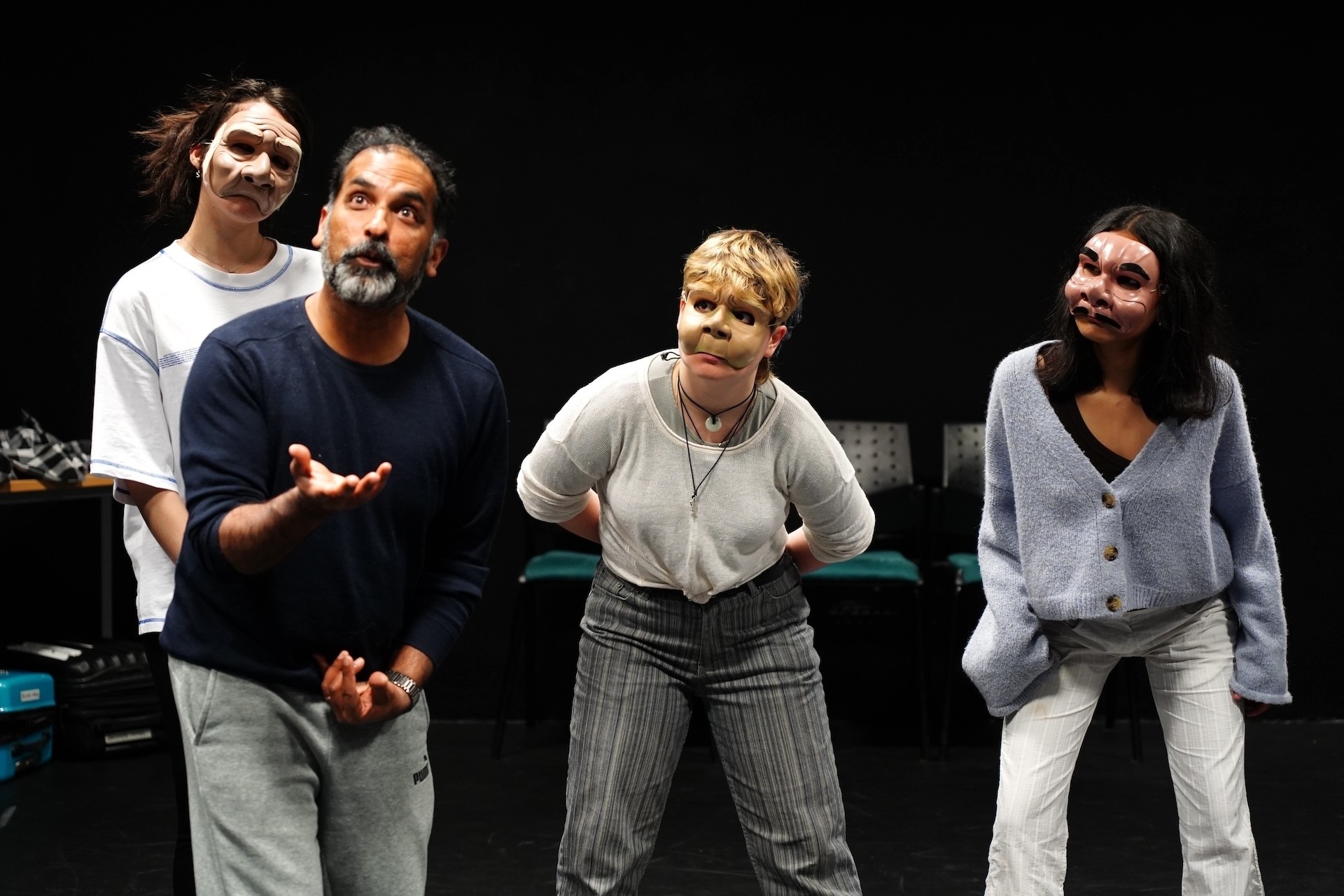 Three students in masks pose behind a man with a beard moving his hands dramatically