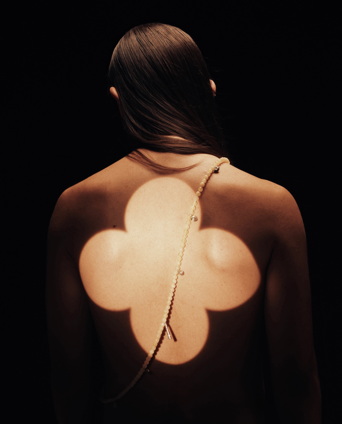 a model facing back showing a long string of beads on their back