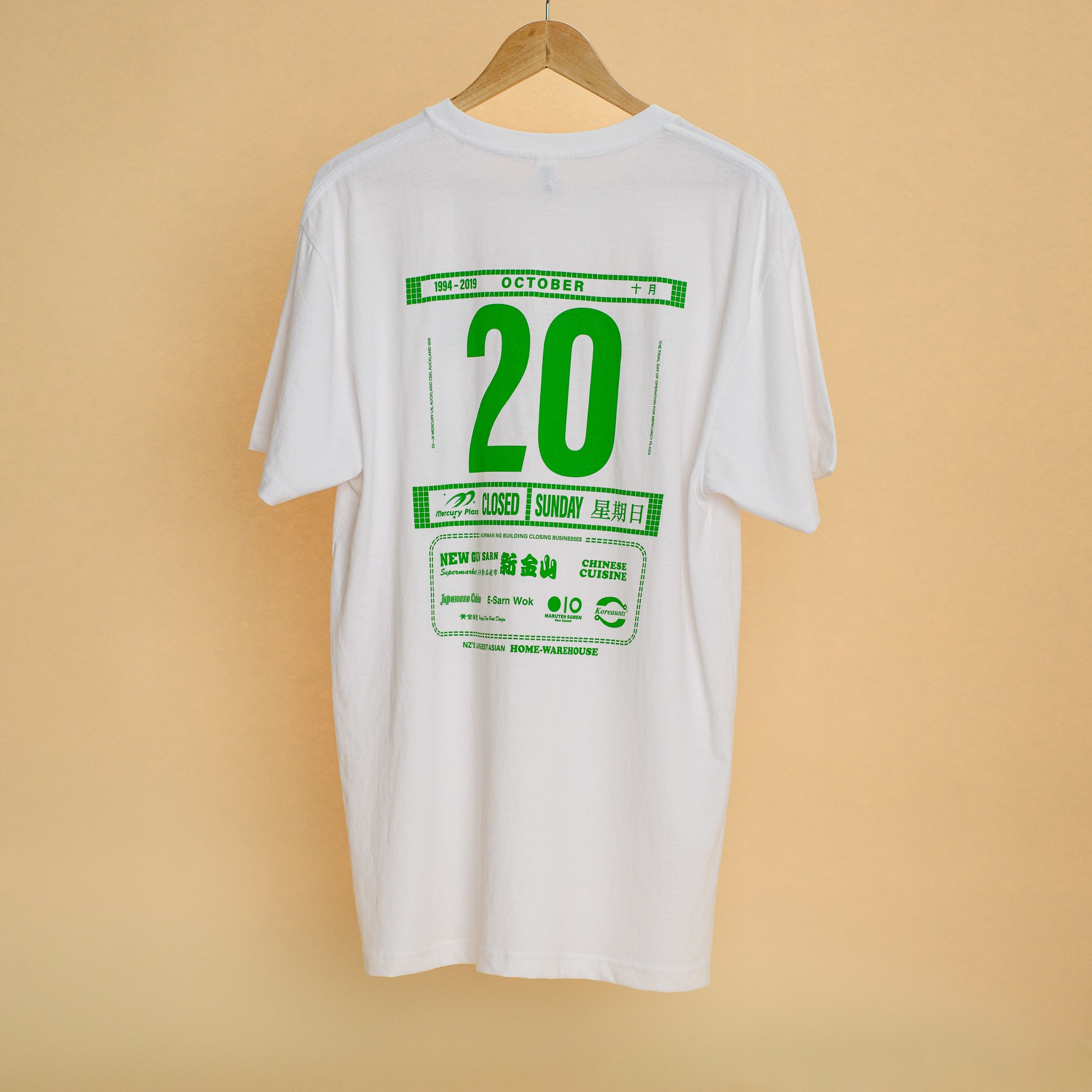 A white t-shirt with a green design in the style of a Chinese rice paper calendar