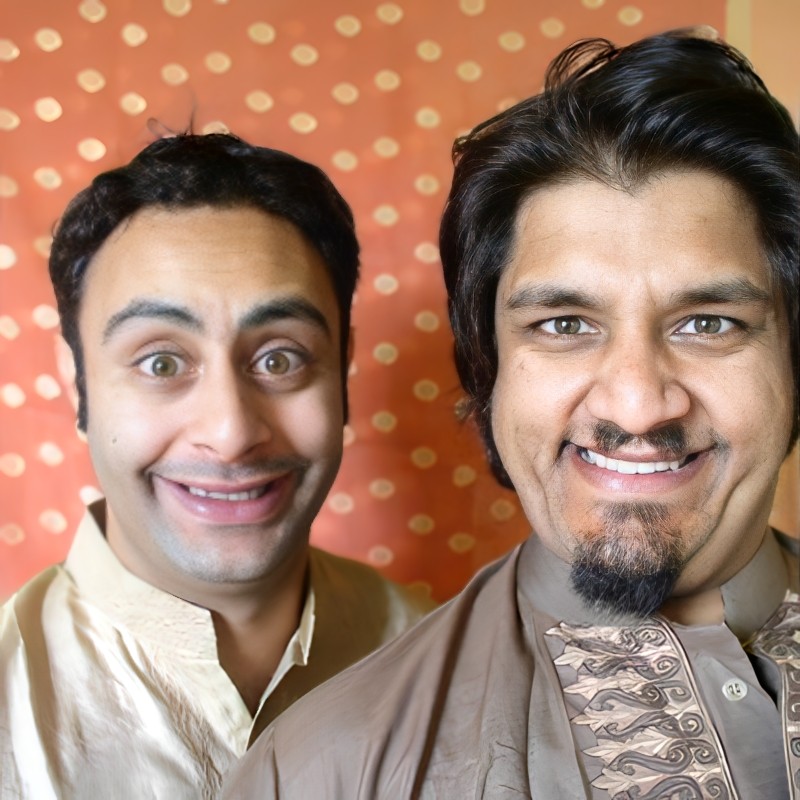 Two smiling Indian men wearing kurta against an orange background.