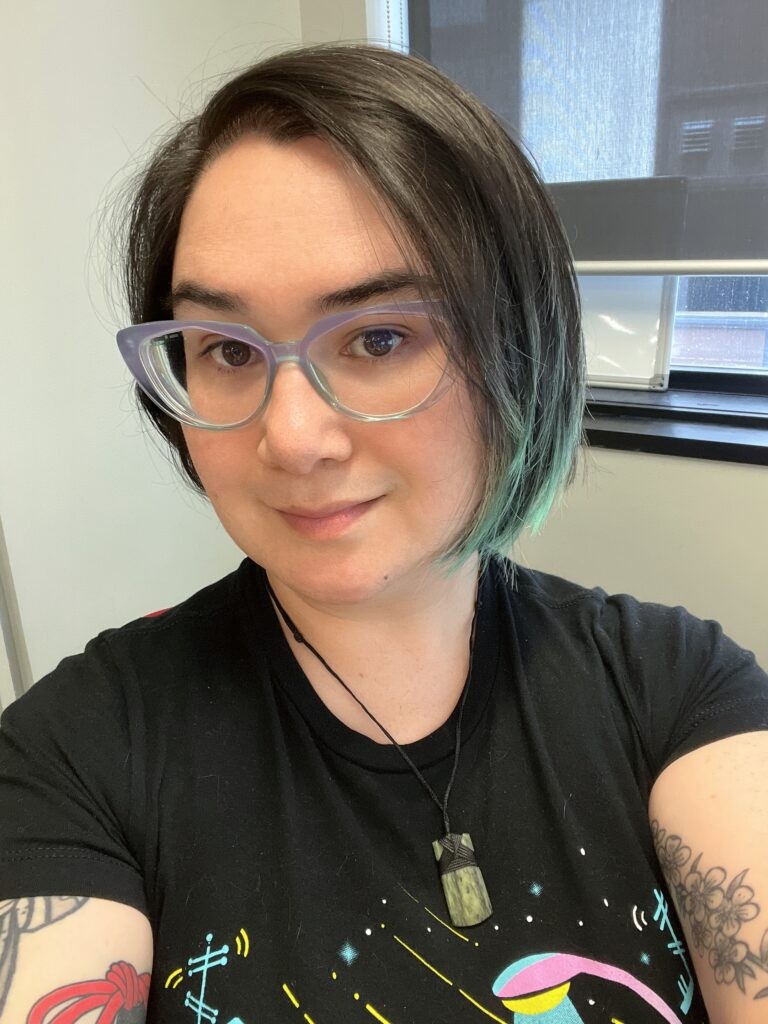 A selfie of a person with glasses and black hair that has been dyed green at the bottom.