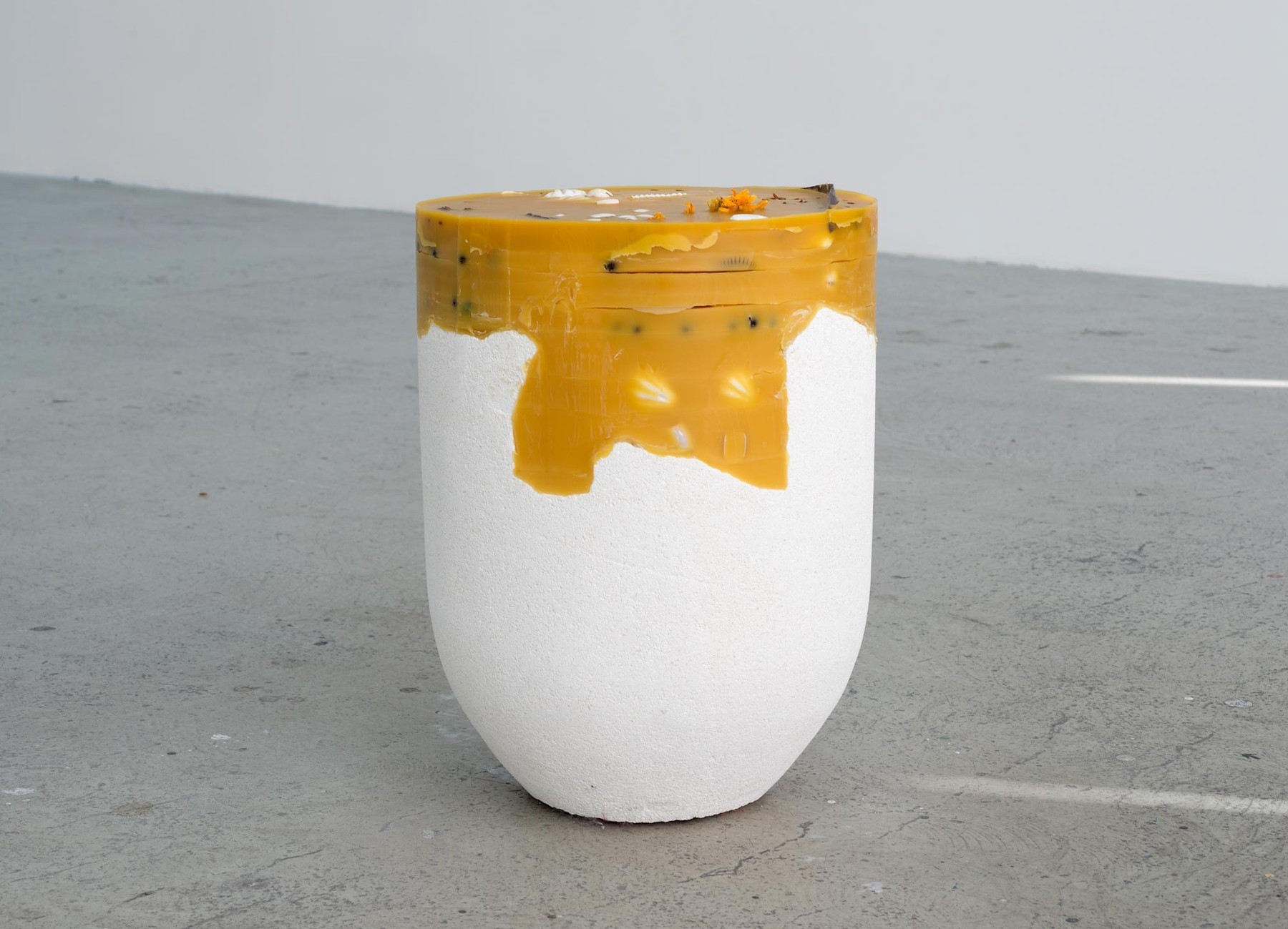 A white plaster pot with a orange beeswax top jaggedly filled with remnants