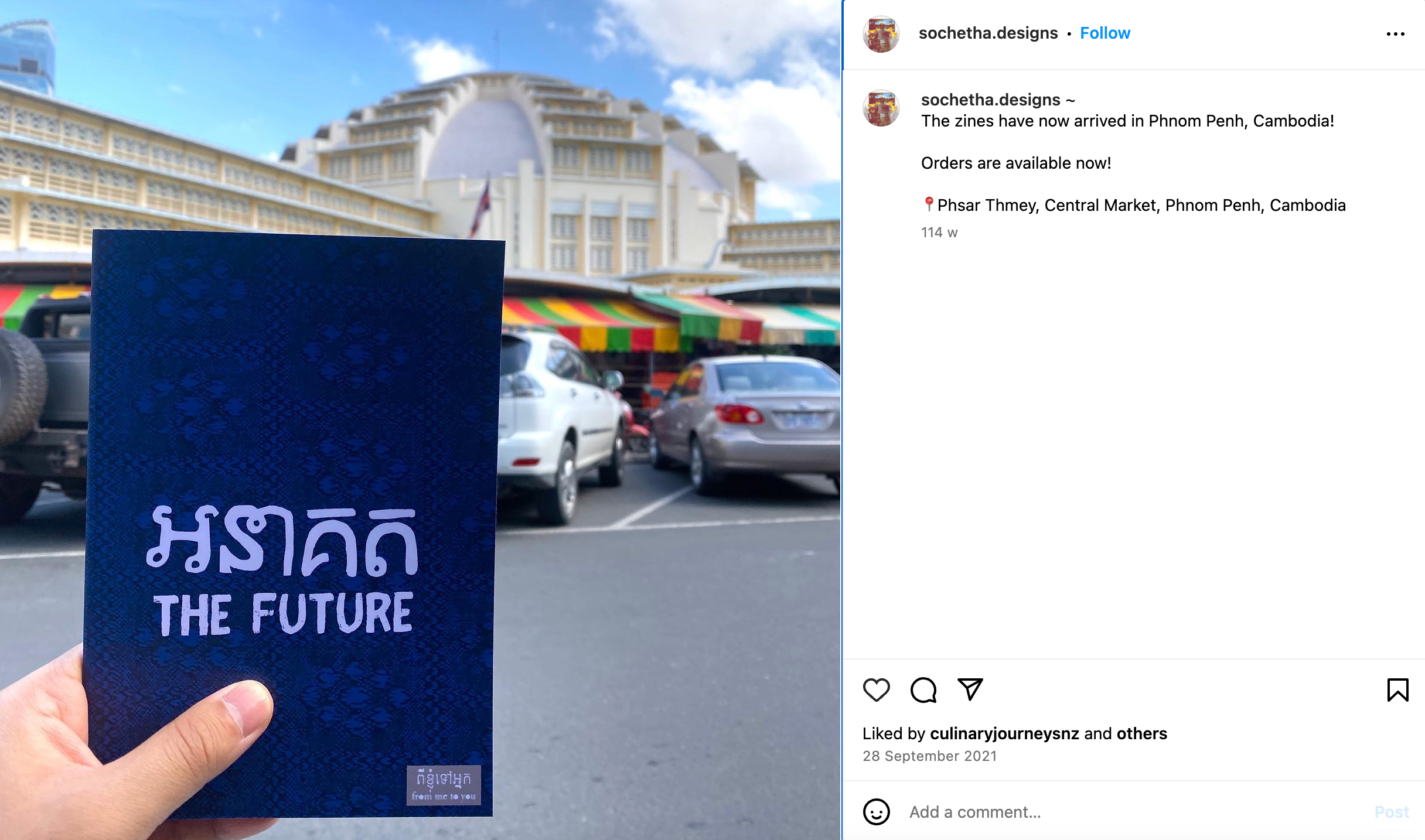 A hand holding a zine in front of Cambodian buildings.