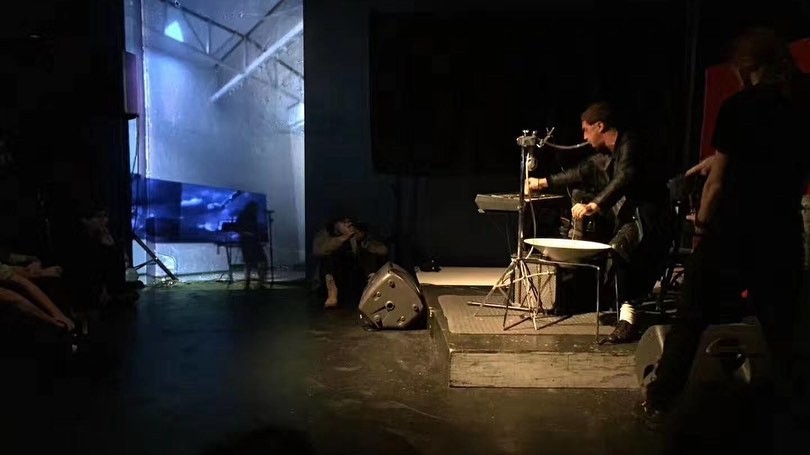 A man playing drums in front of a video projection