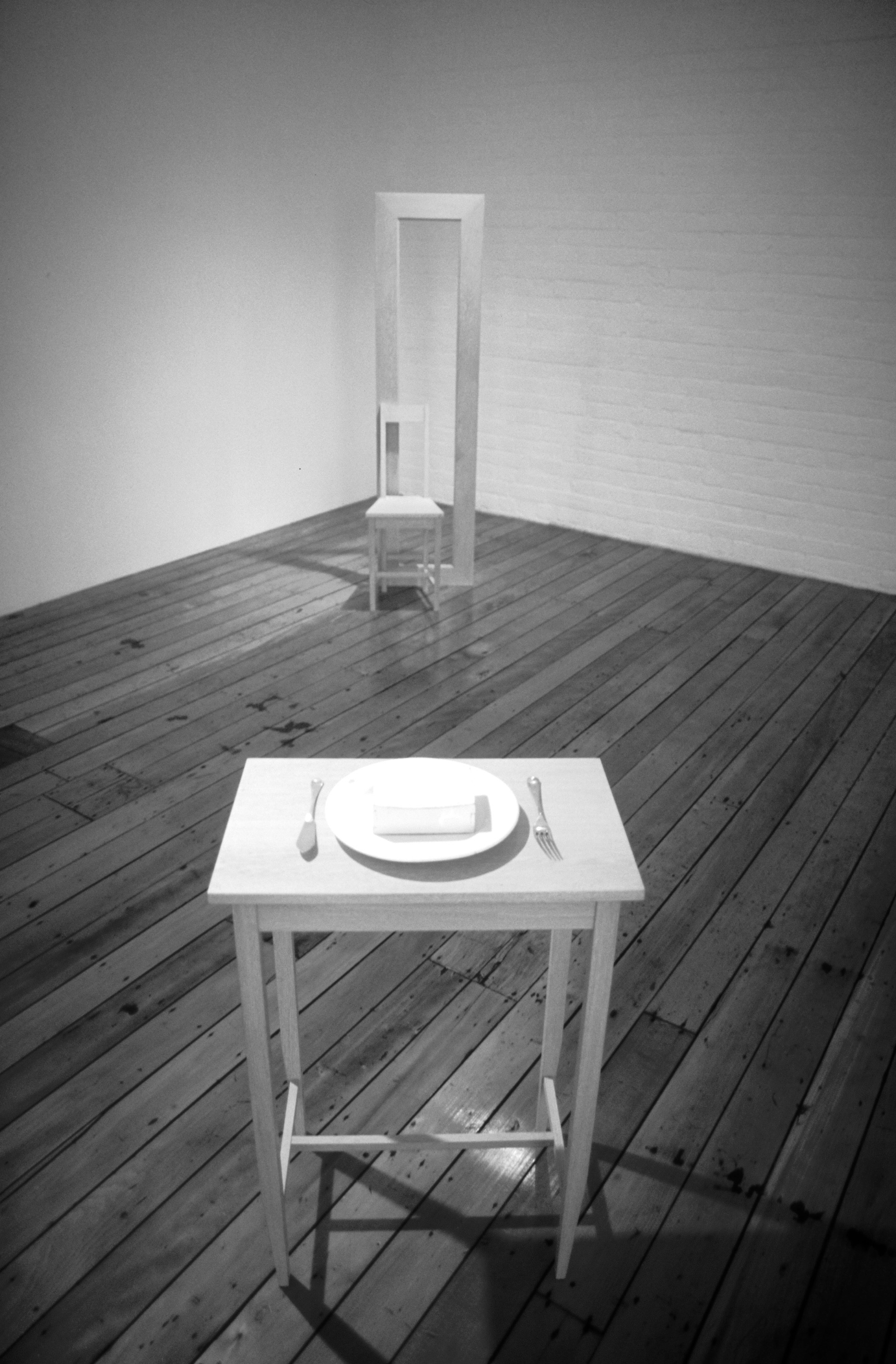 a plate with fork and knife on a small table, with a chair with high back far away