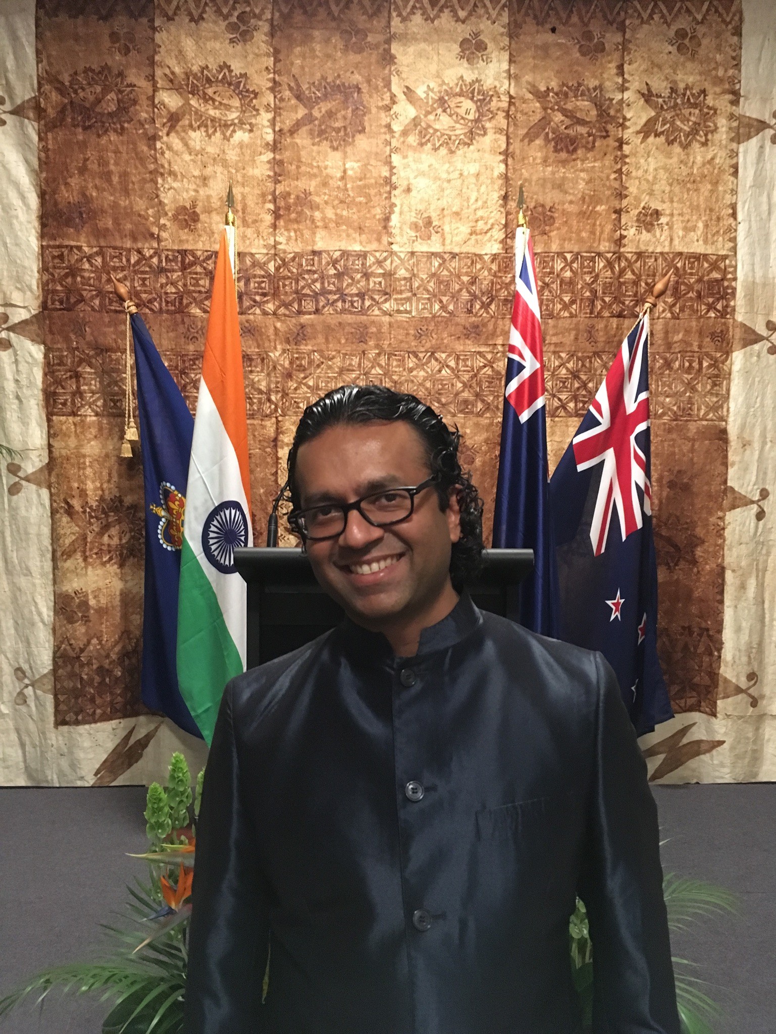 A man standing in front of a podium with flags in the background
