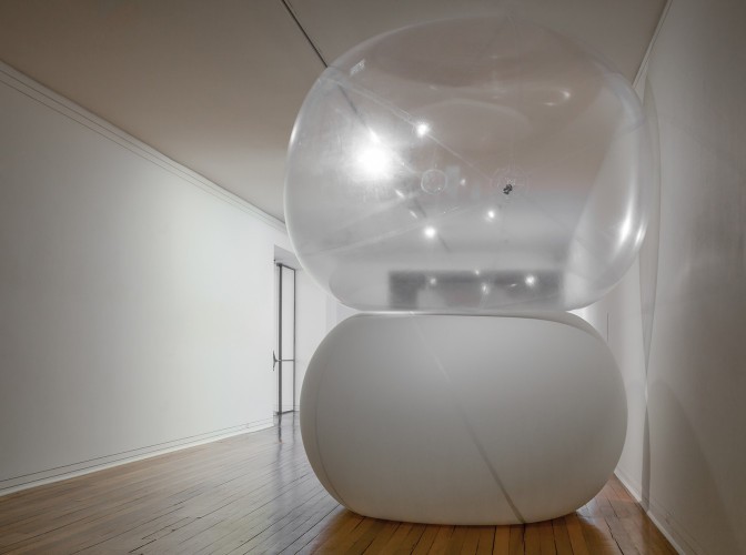 Two large inflated orbs, the bottom white and top translucent, stacked on top of each other sandwiched between the floor and ceiling.