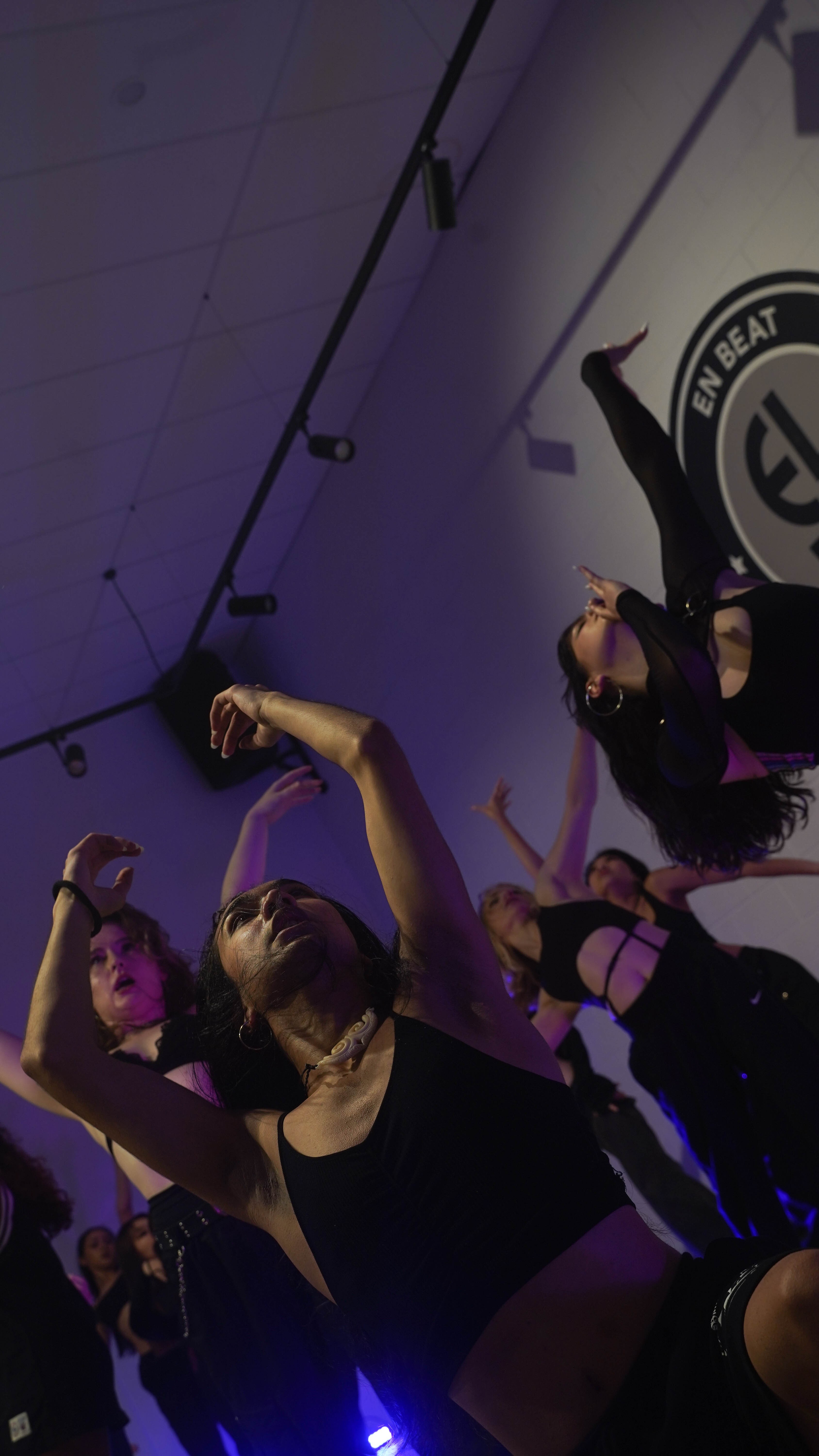 A group of people dancing in the studio with moody purple lighting