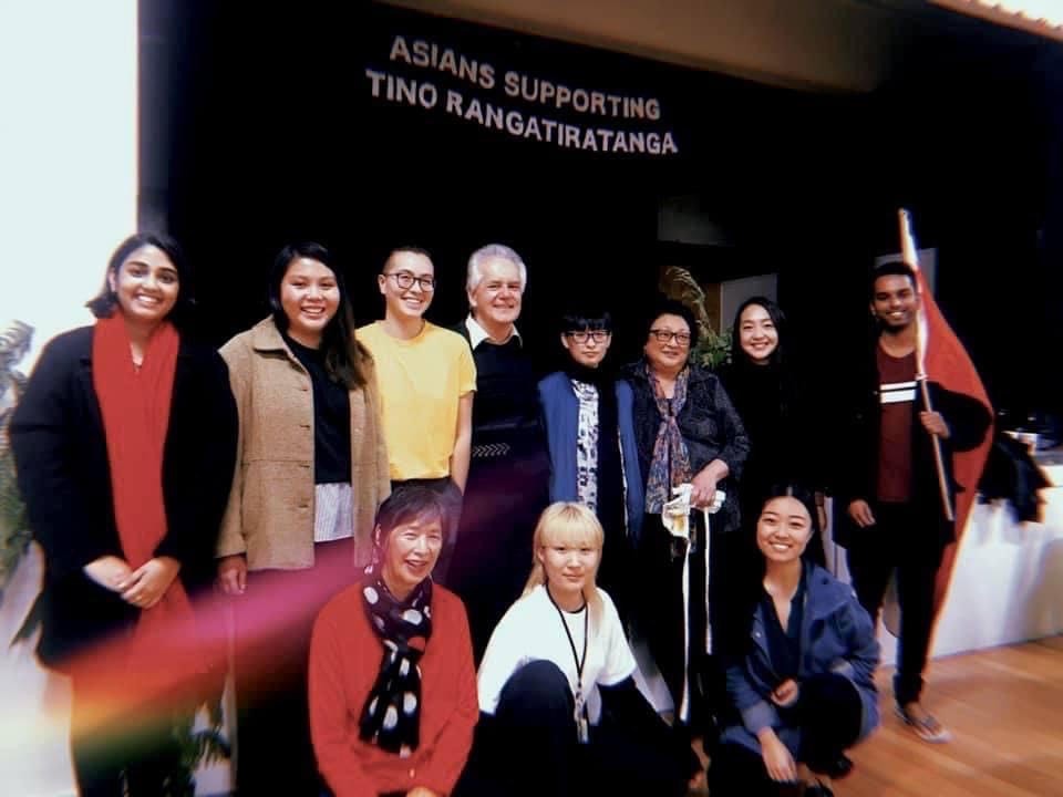 Group photo in front of a stage with the Asians Supporting Tino Rangatiratanga banner in the background.