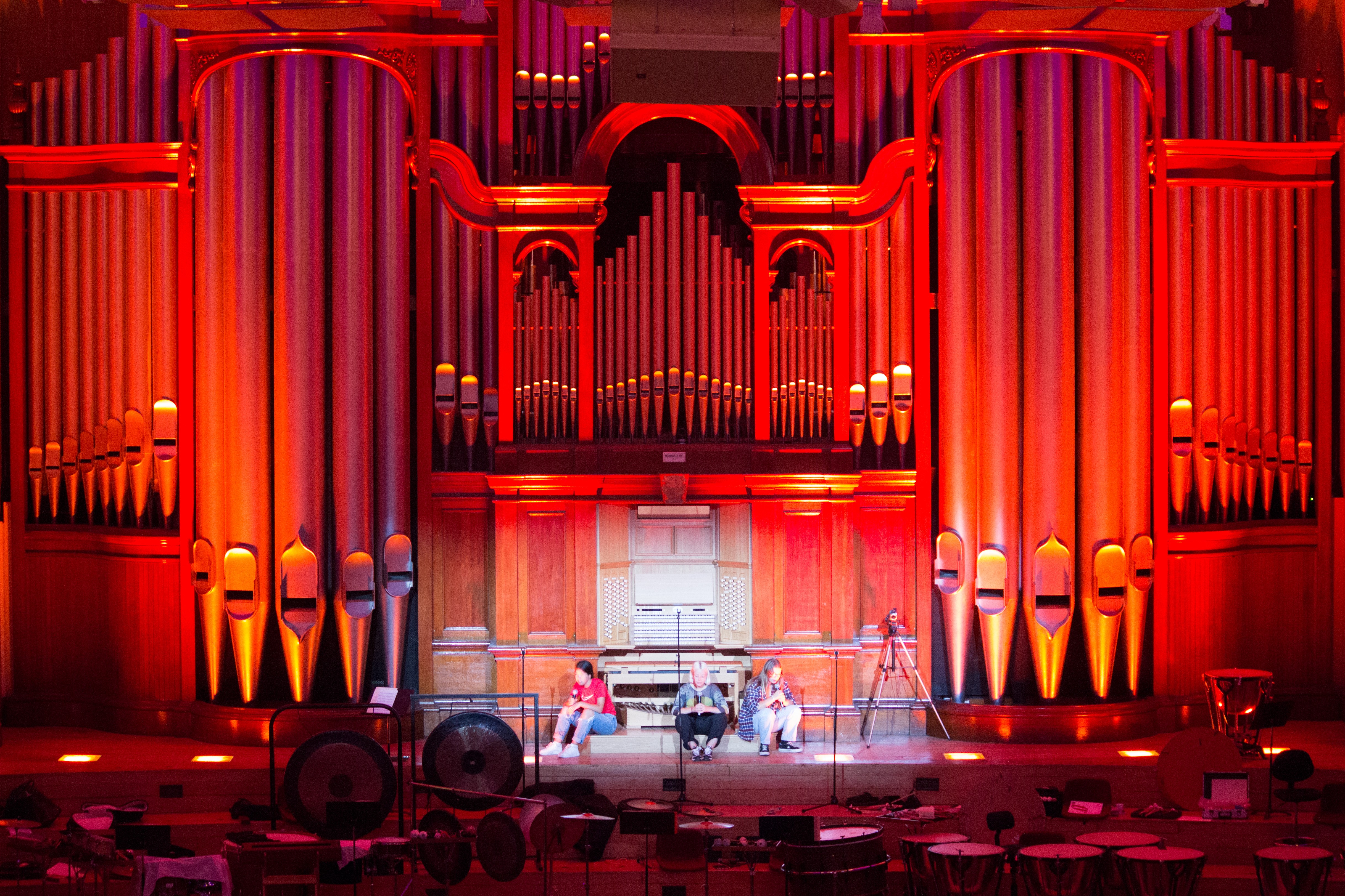 A few poets sit in front of the lit-up organ at Auckland Town Hall.