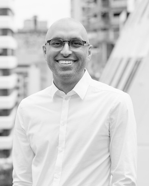 A smiling man wearing glasses and a white shirt