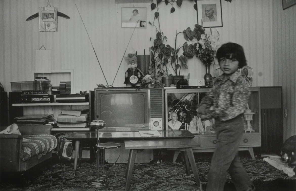 a black and white photo of a boy walking through a highly decorated lounge