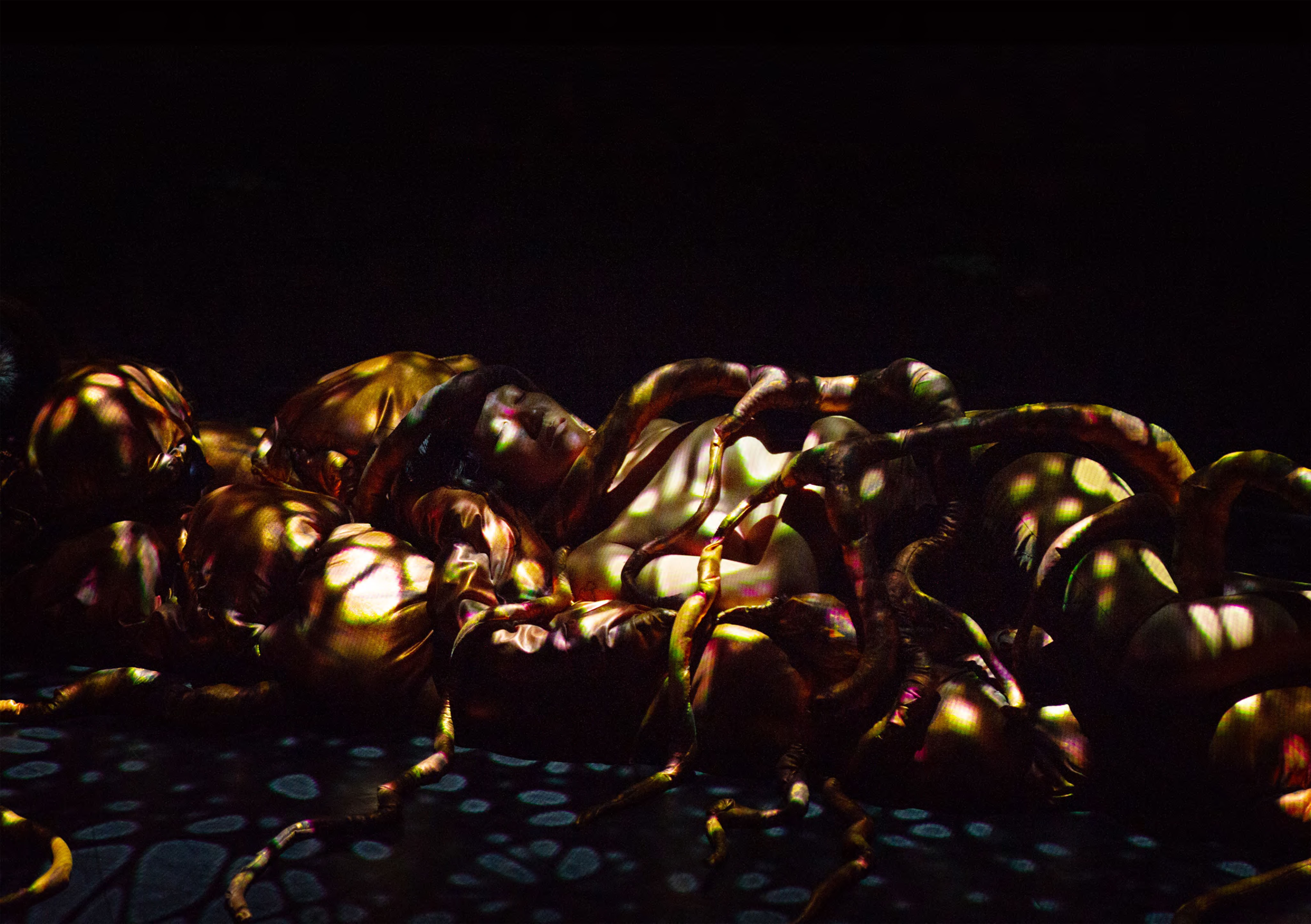 A man lies under snake-like puppets