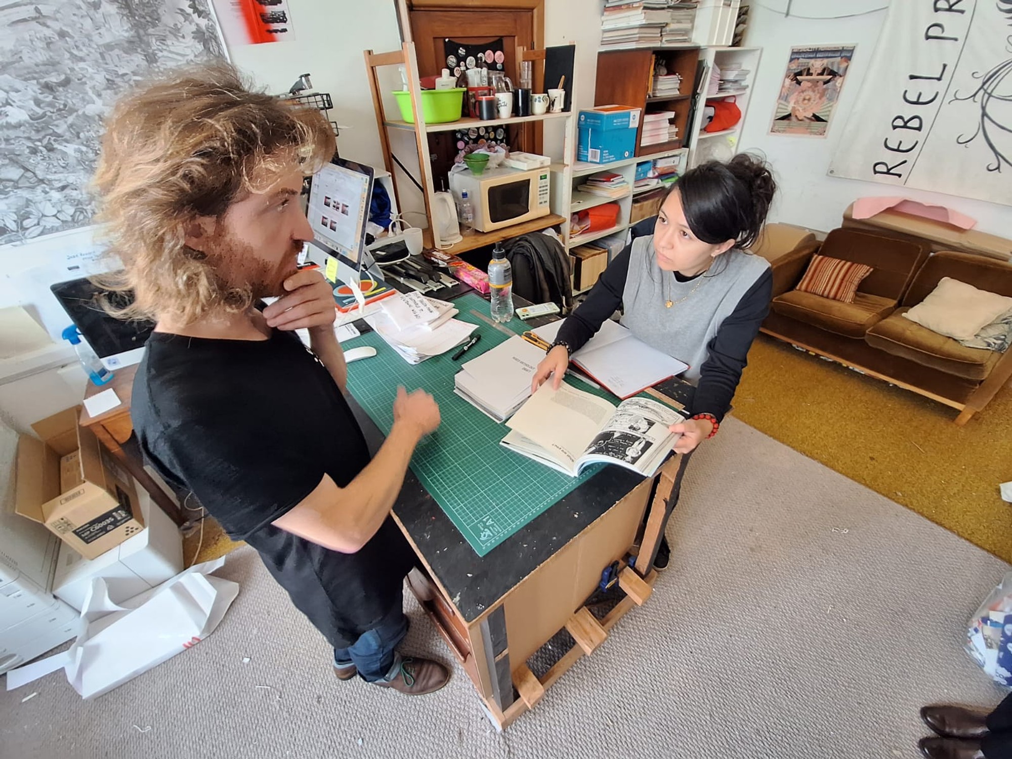 Jennifer and Achille in the print studio looking at a copy of a book together.