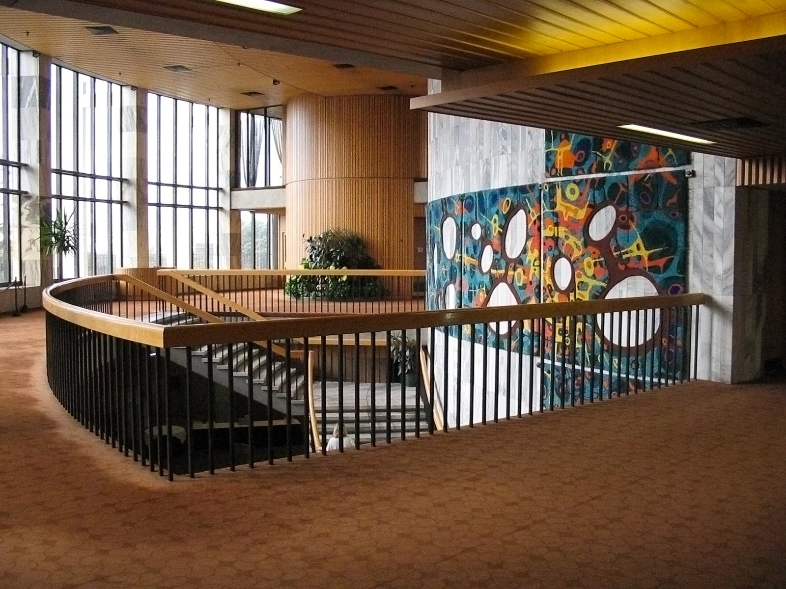 A colourful tapestry of square panels with round cutouts curves around the central stairwell at Parliament.