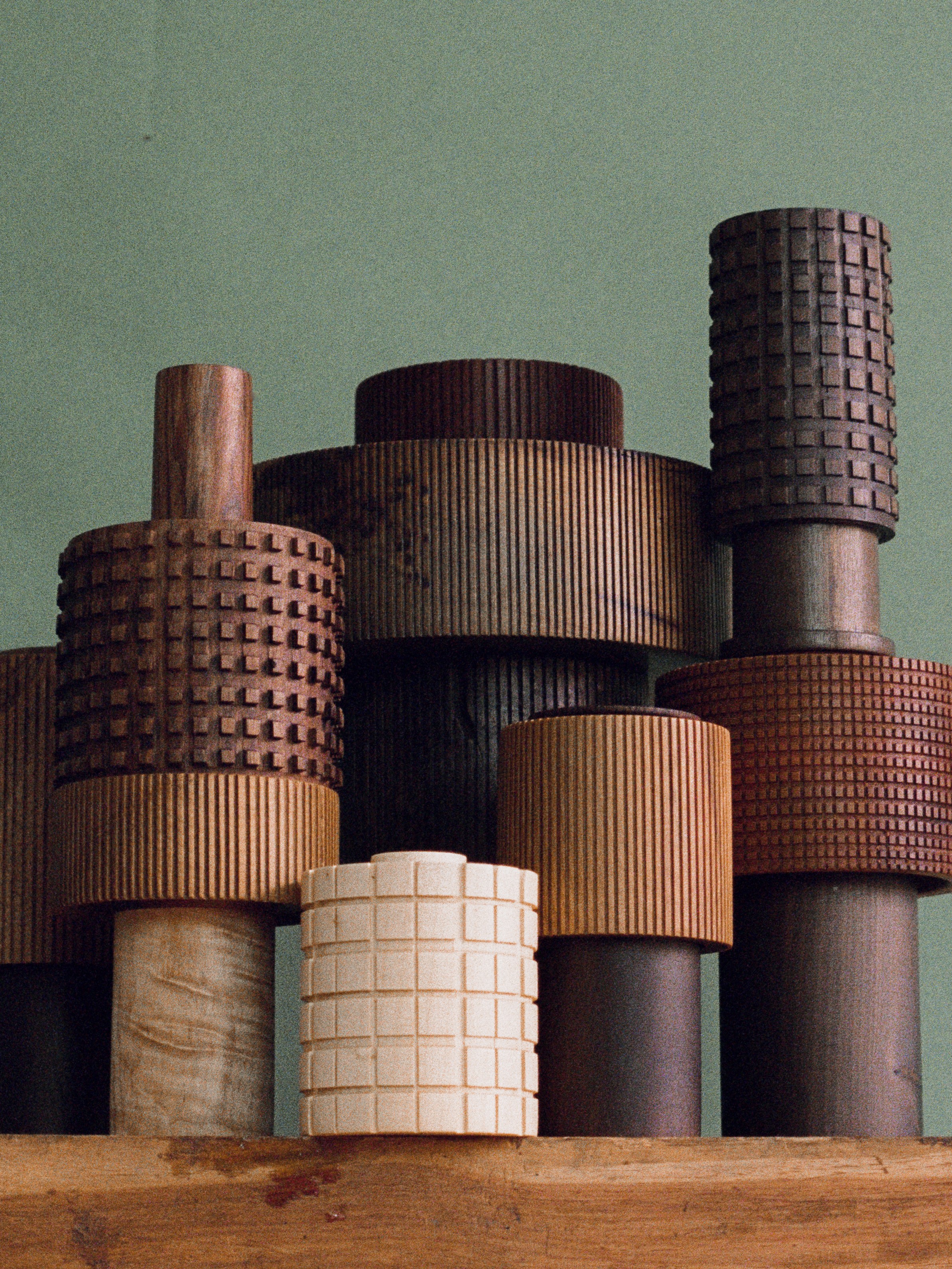 A series of cylindrical wooden objects with gridded and lined carvings decorating them