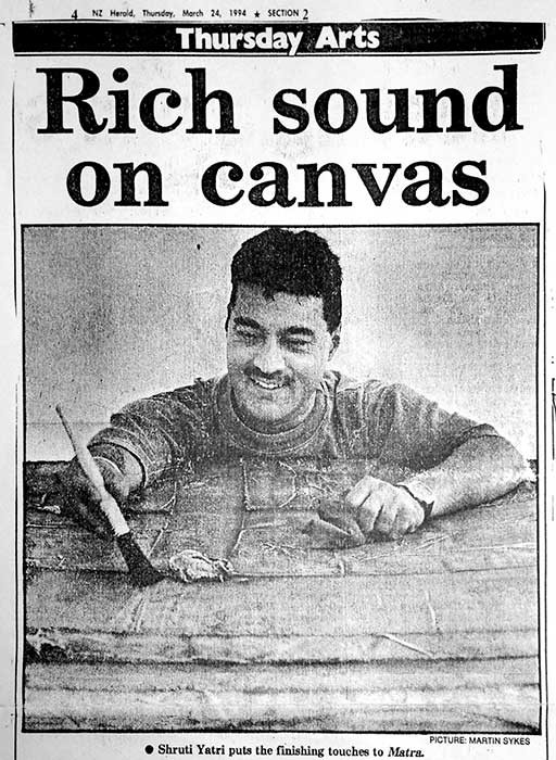 Newspaper clipping with an image of a man painting on a canvas.