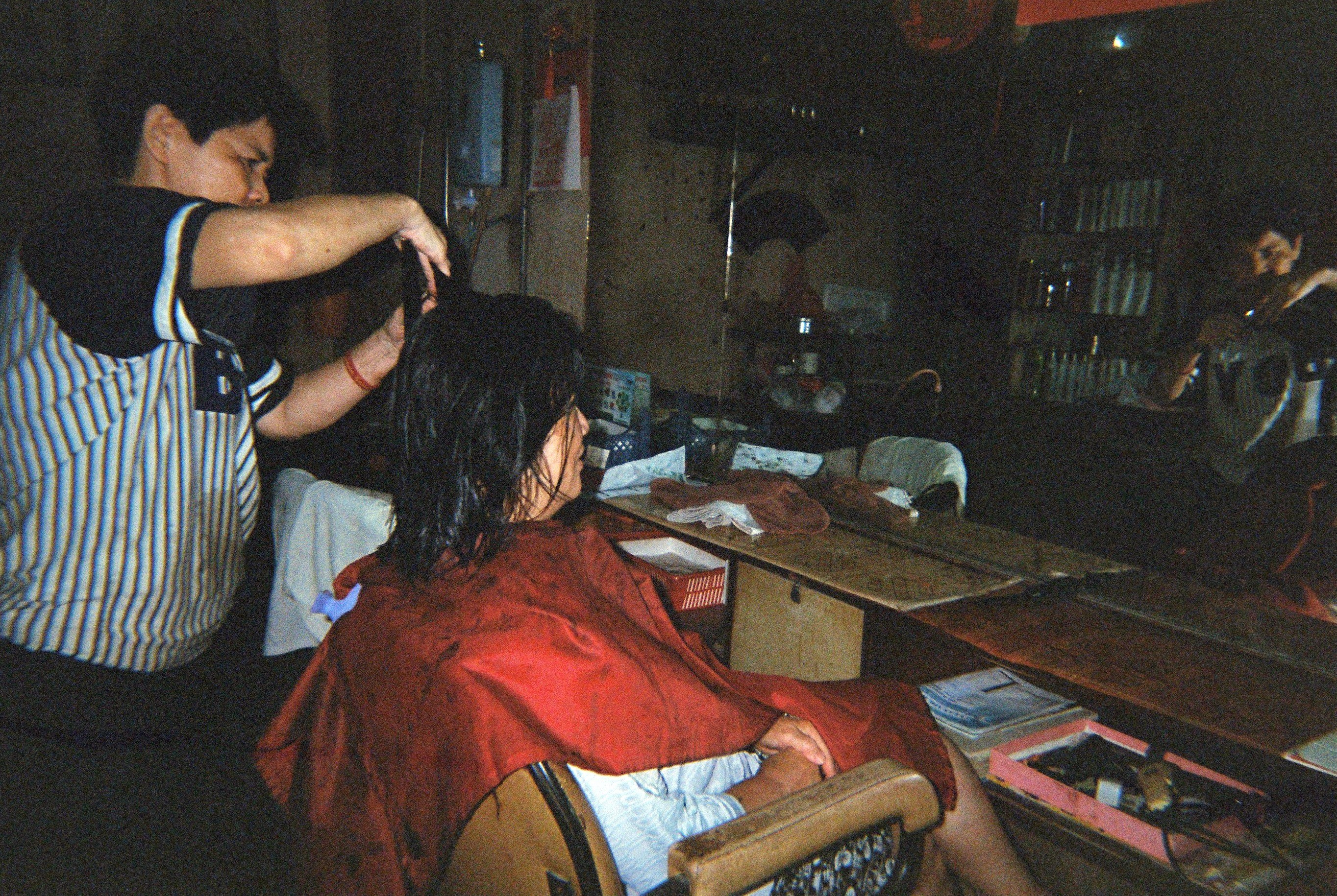 Photo of a woman in a hairdressing chair getting her hair cut.