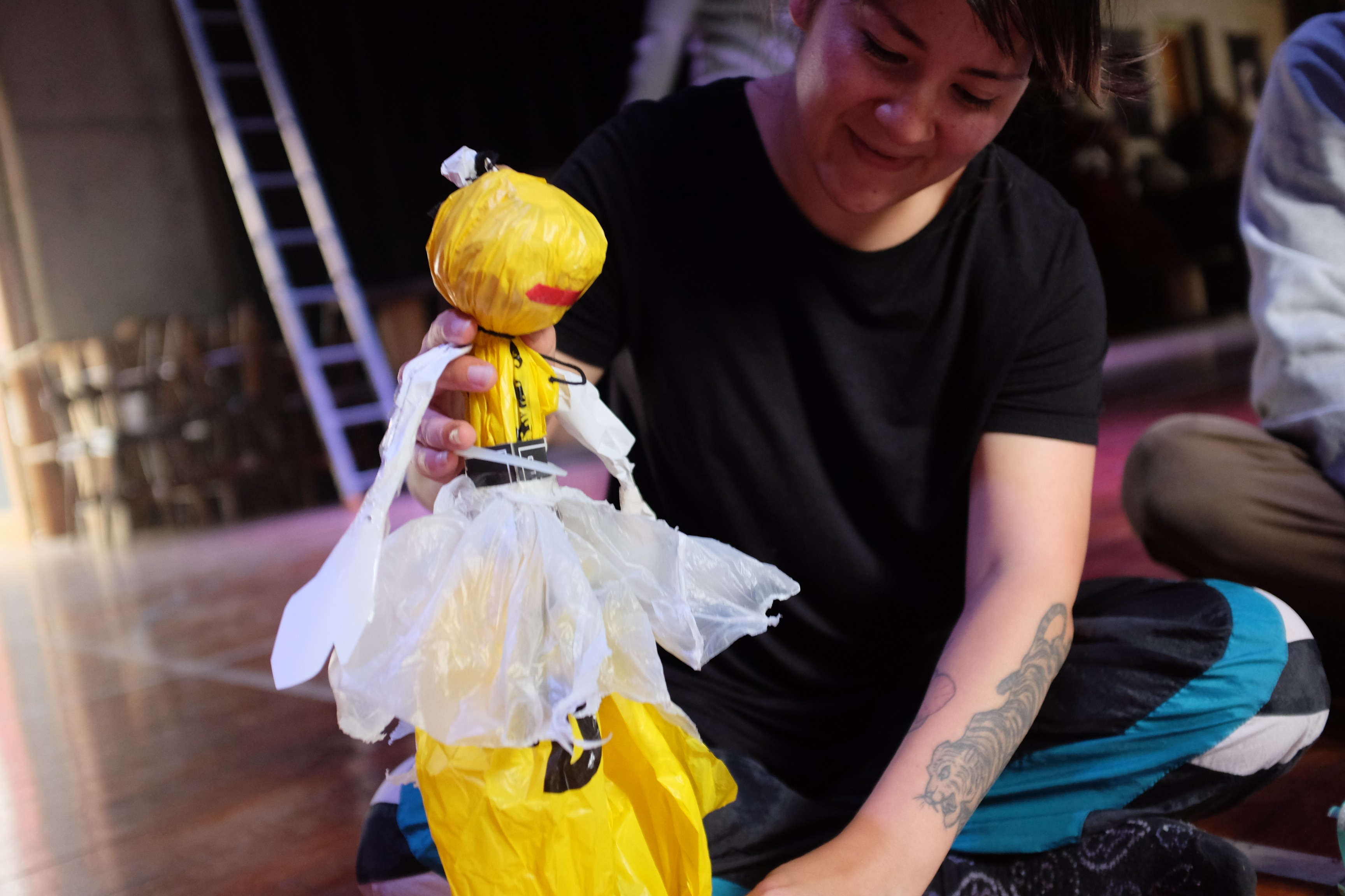 A woman sitting on the ground holding a small yellow puppet figure