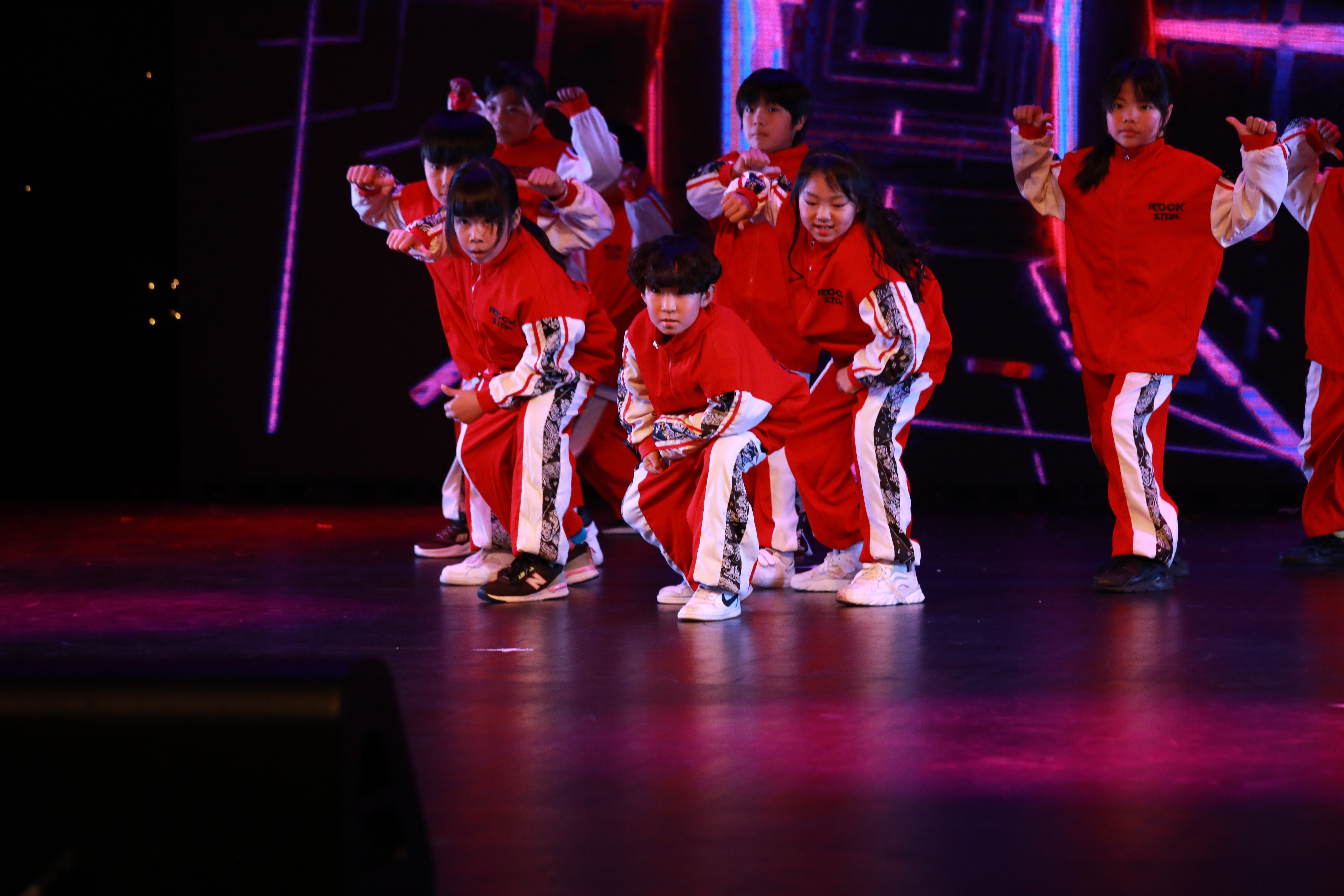 A group of young people in matching red tracksuits on stage