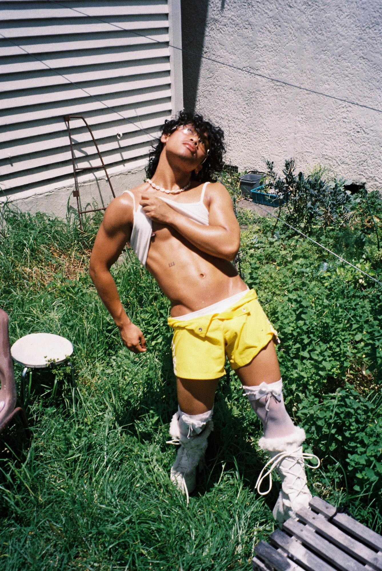 Muscular Filipino-looking person in skimpy clothes posing in a garden