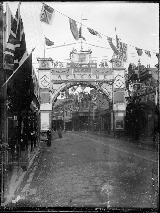 Black and white photograph of a temporary decorative arch spanning a street