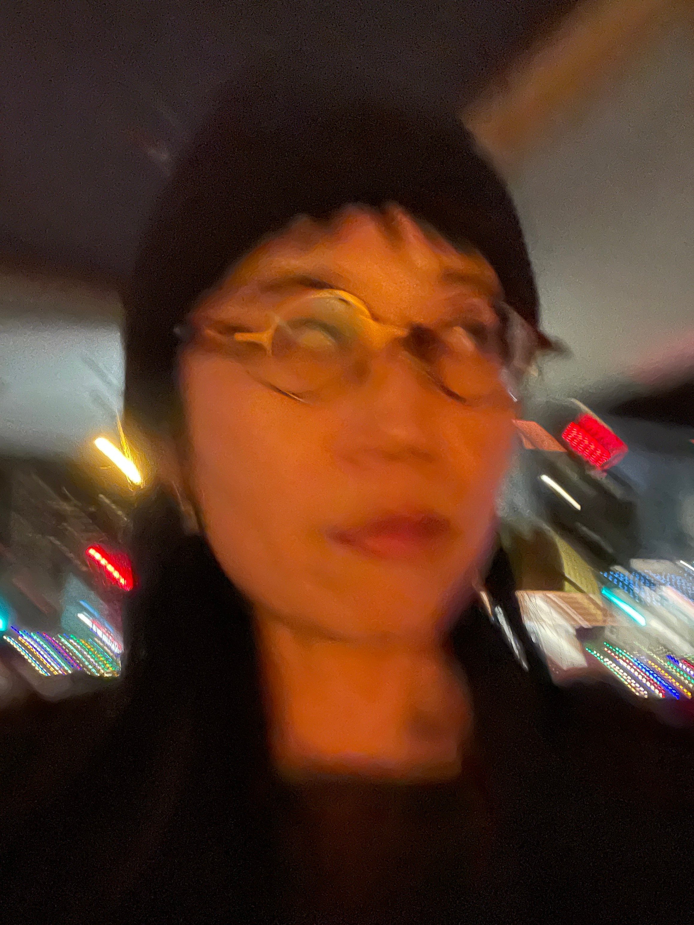 Blurry portrait photo of a woman wearing glasses with city lights in the background.