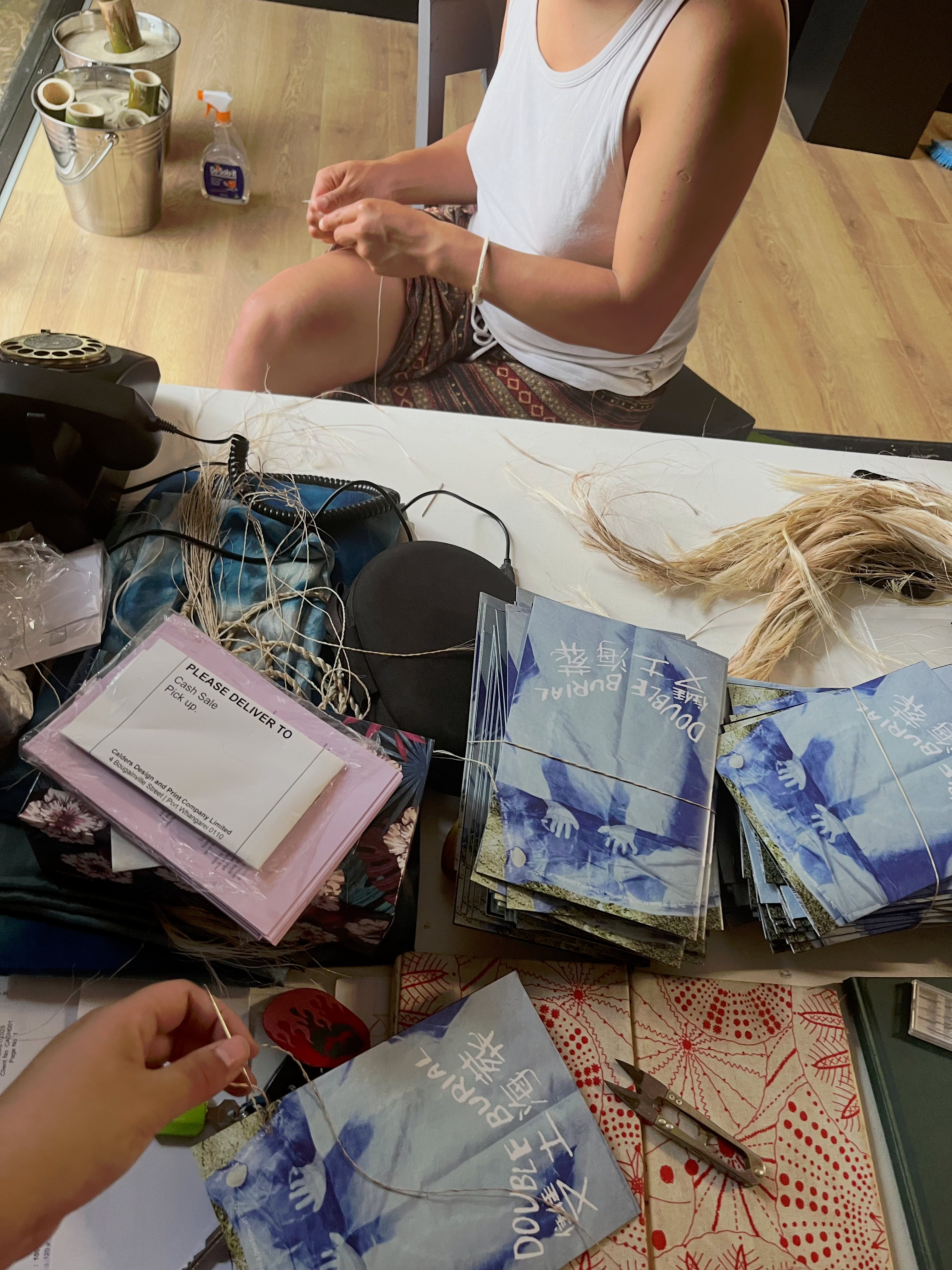 Close up of two people tying muka to books