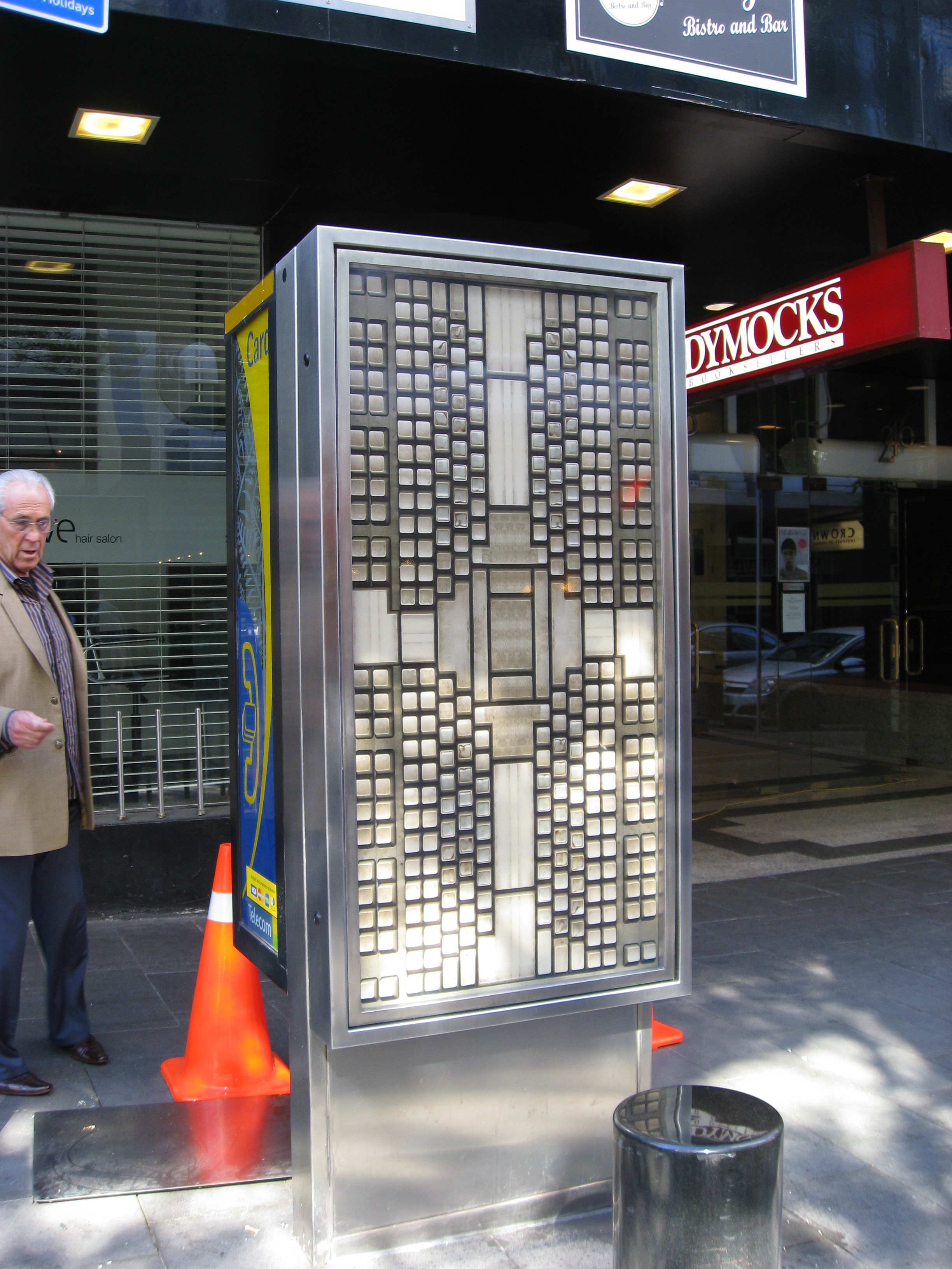 A print of computer keyboards in a cross shape inside a Telecom phone booth.