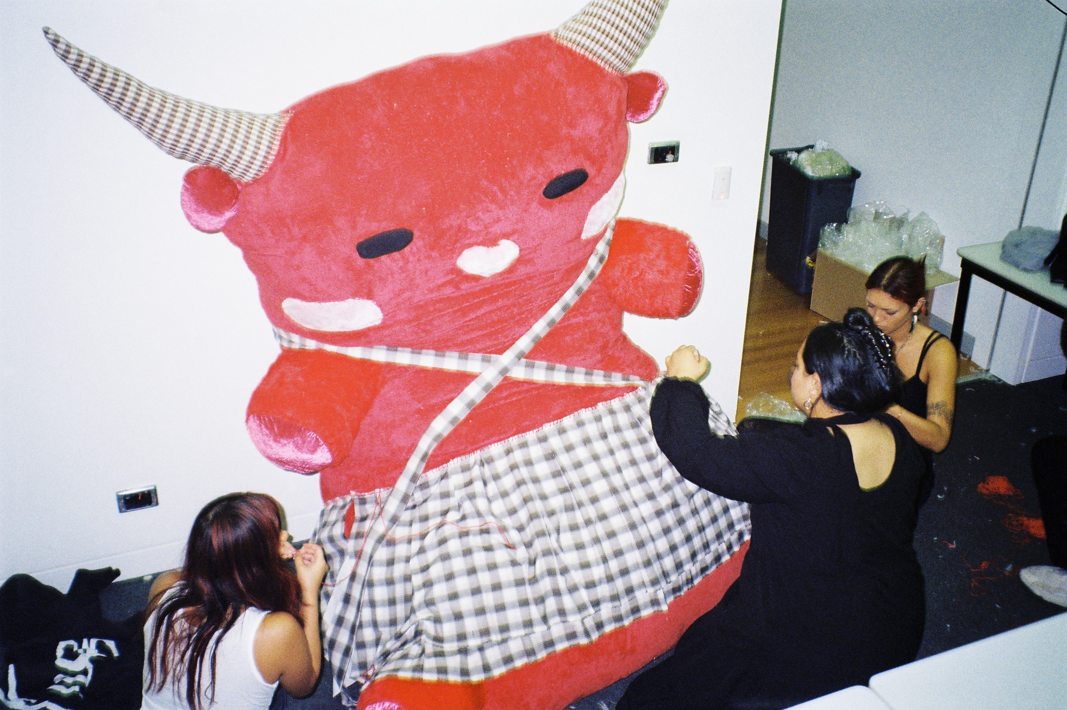 A large red soft toy with people around it