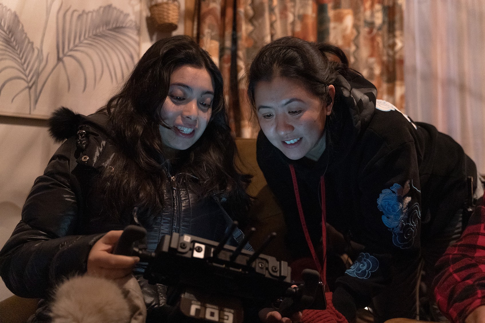 Two female-presenting people looking at a screen and smiling