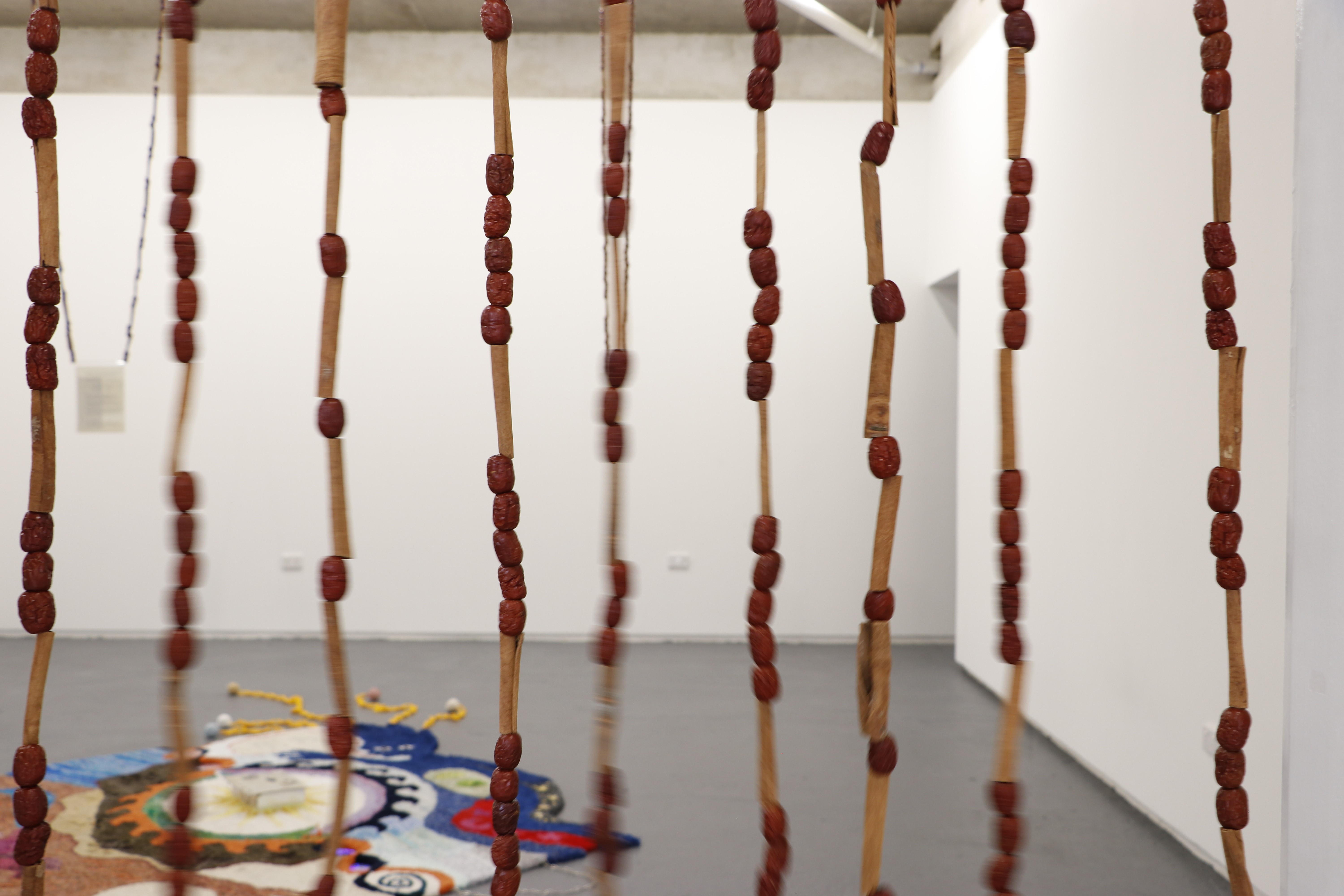 A beaded curtain of jujubes sways in the foreground with a colourful rug in the background.