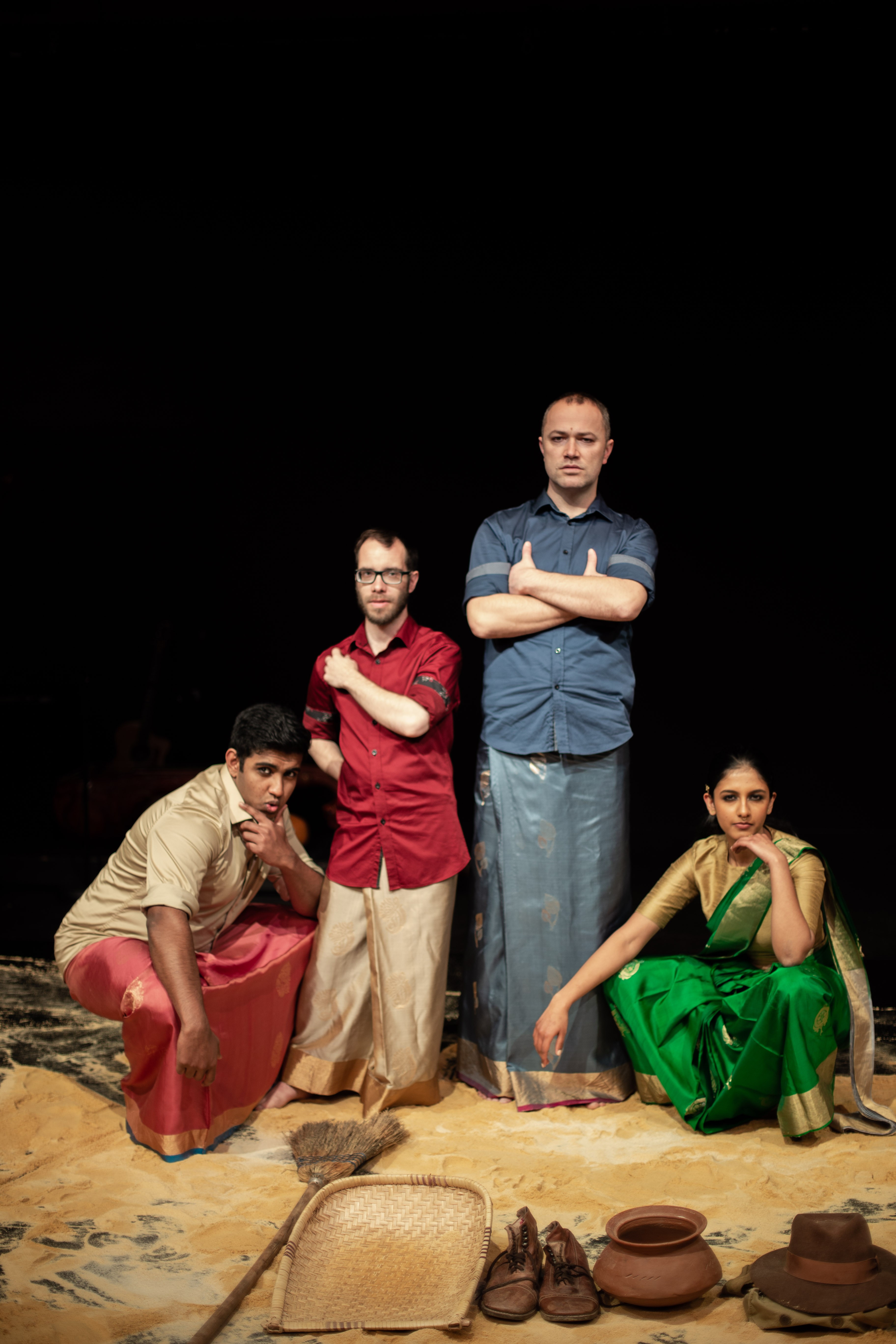 Photograph of a group of people in South Asian garments on a surface covered in sand