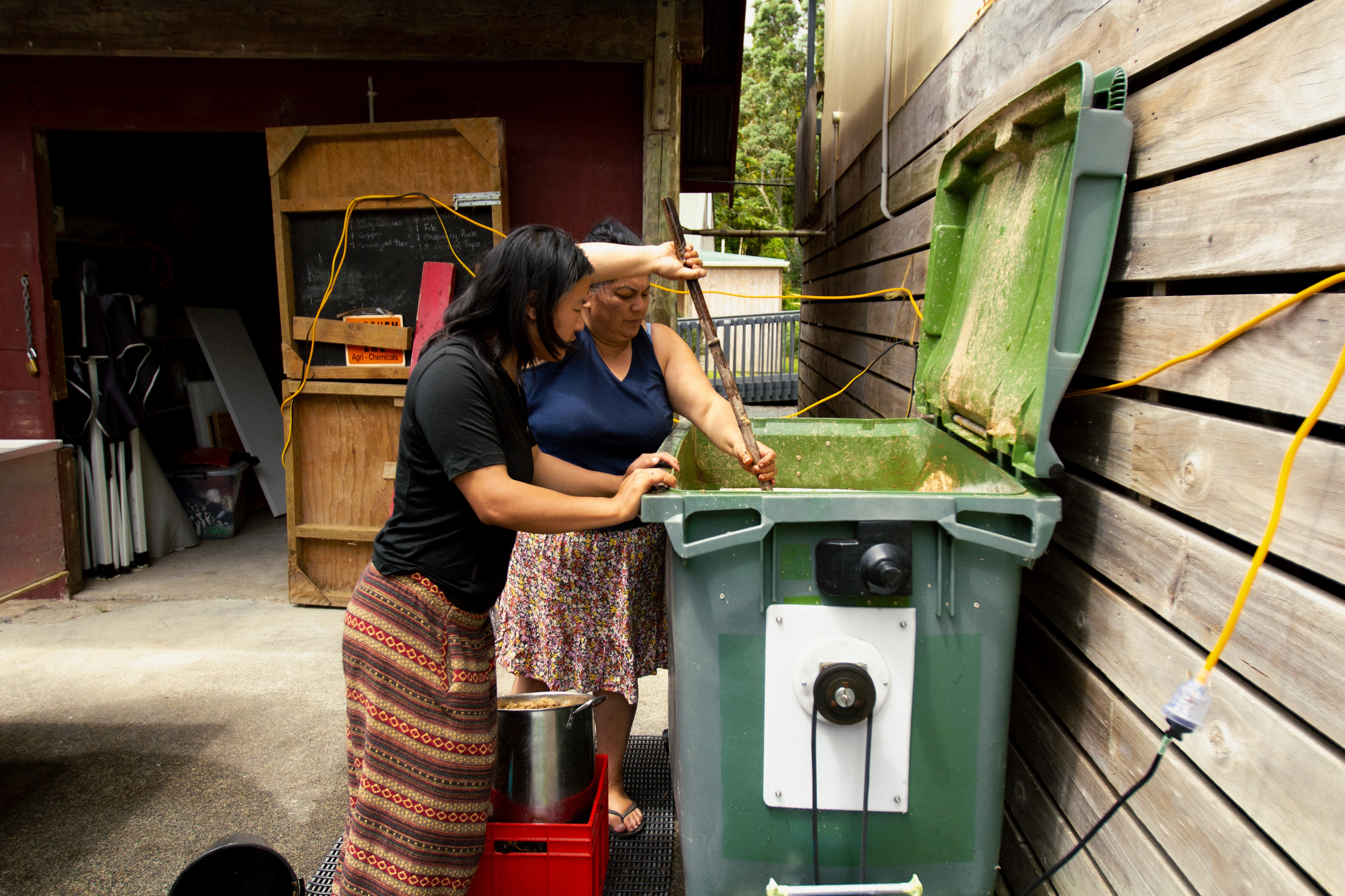 Two people stand over a large container mixing the contents