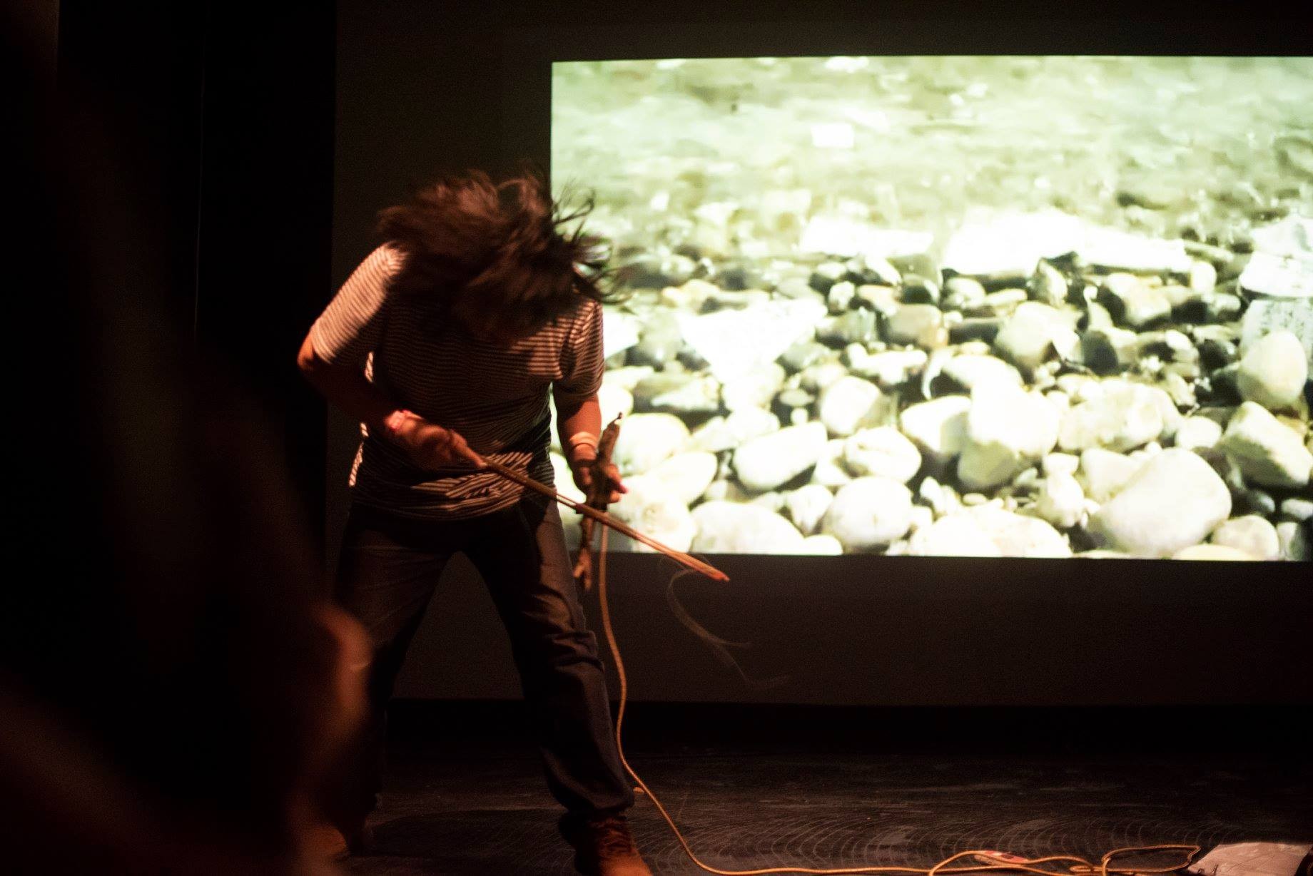 a person in a striped t-shirt performing in front of a projection of rocks