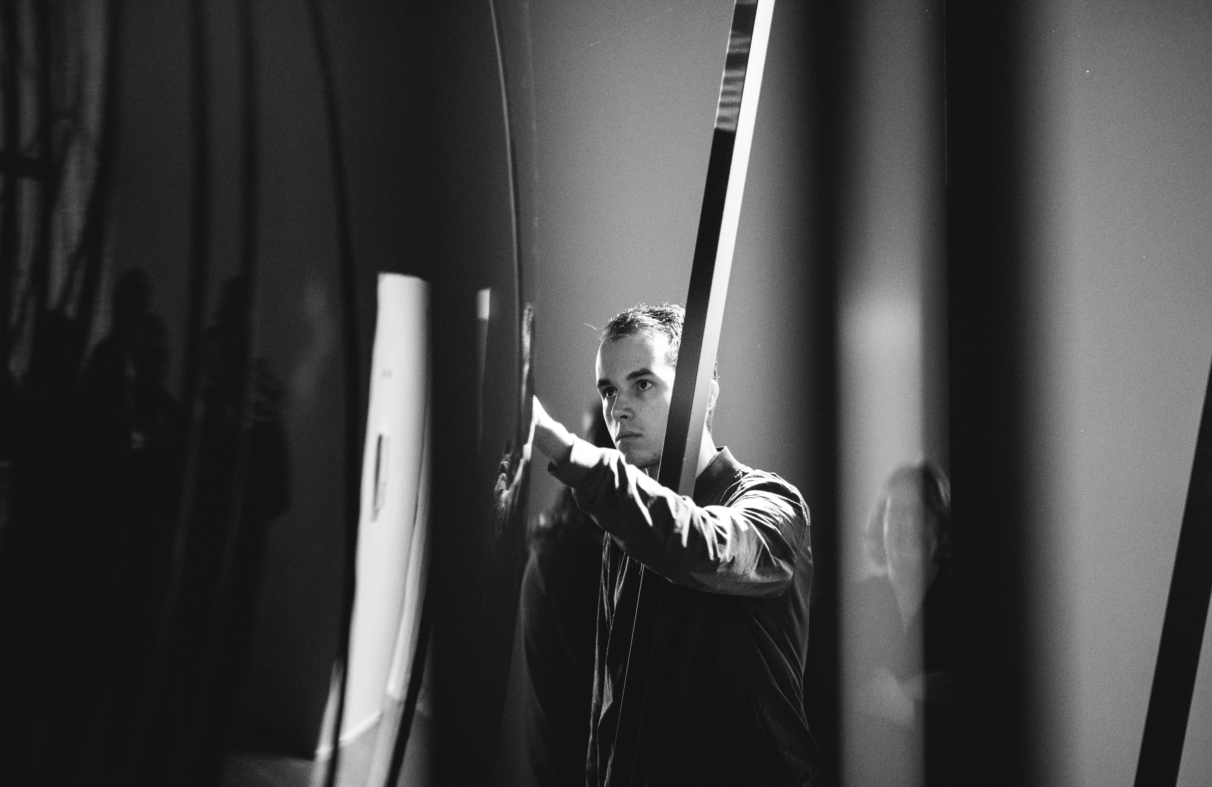 A man stands next to a huge curved piece of glass.