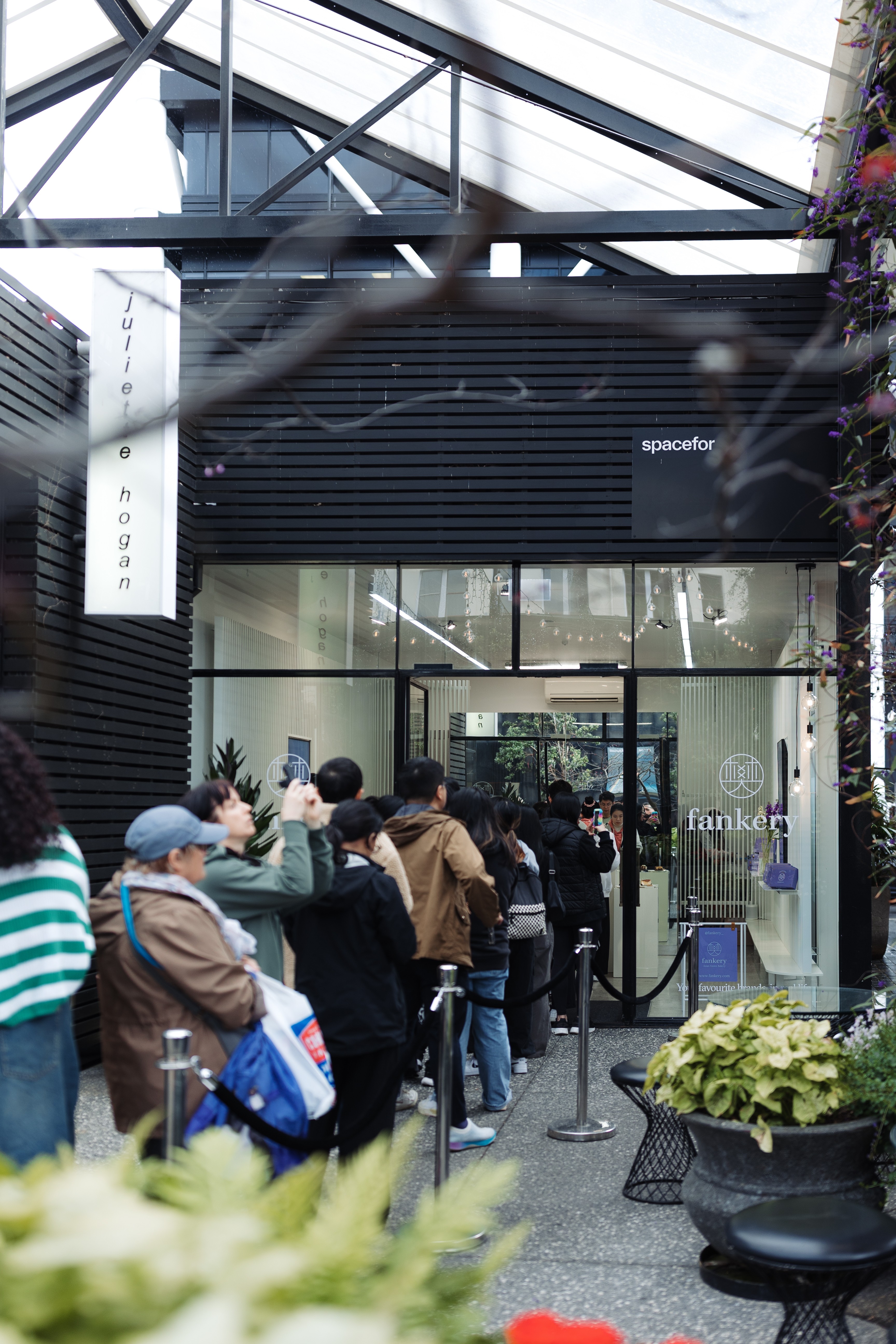 A line of people queue to enter a store.