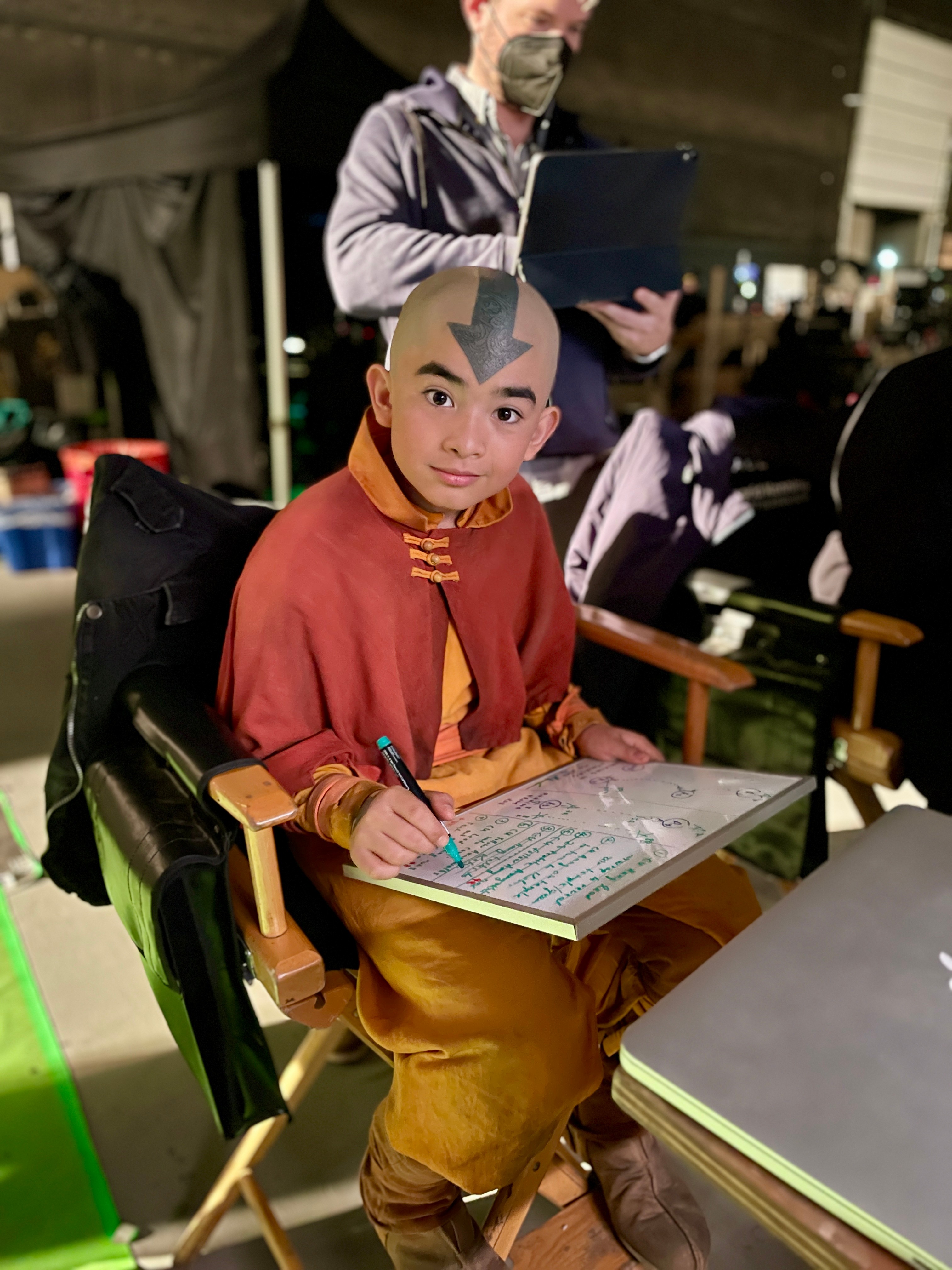 A young man sitting in the director's chair drawing on a whiteboard