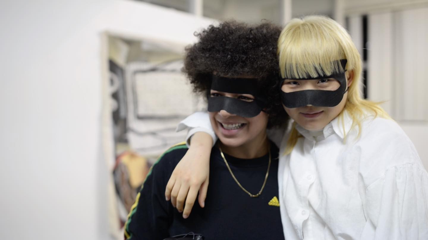 two people in black masks smiling at the camera