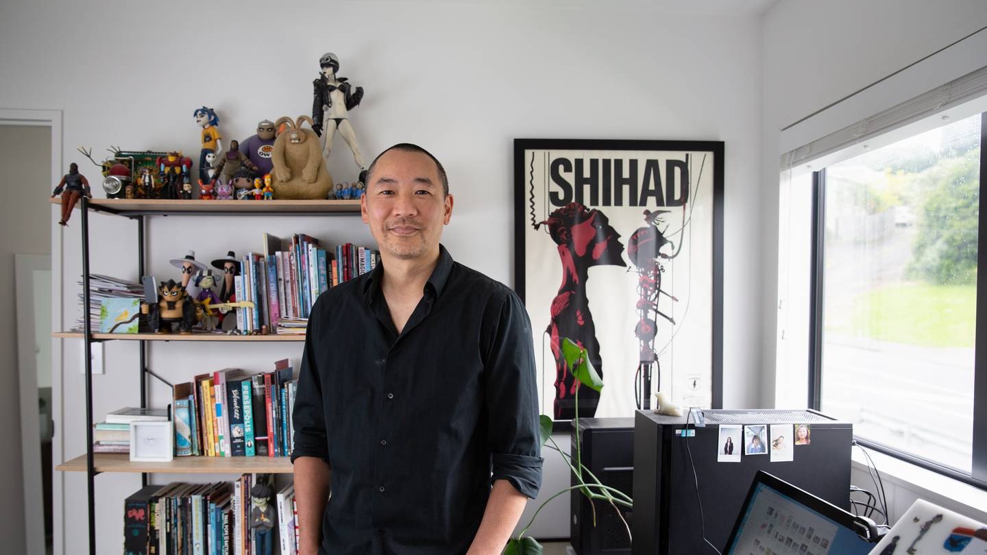 A man standing in an arts studio in front of a book shelf.