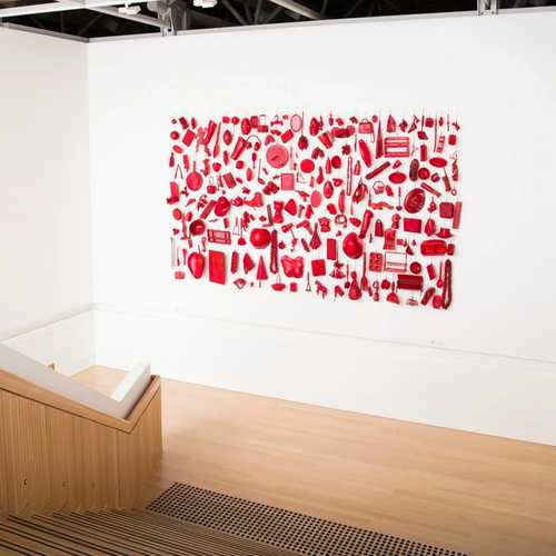 Red dipped objects are hung in a rectangle on a stairway in Te Papa.